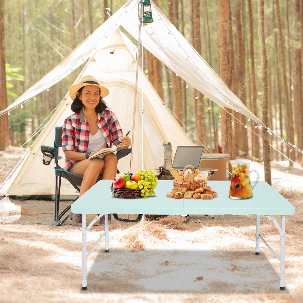 Frau im Campingzelt, sitzt auf einem Stuhl, schreibt, ein Tisch mit Obst und Brot.