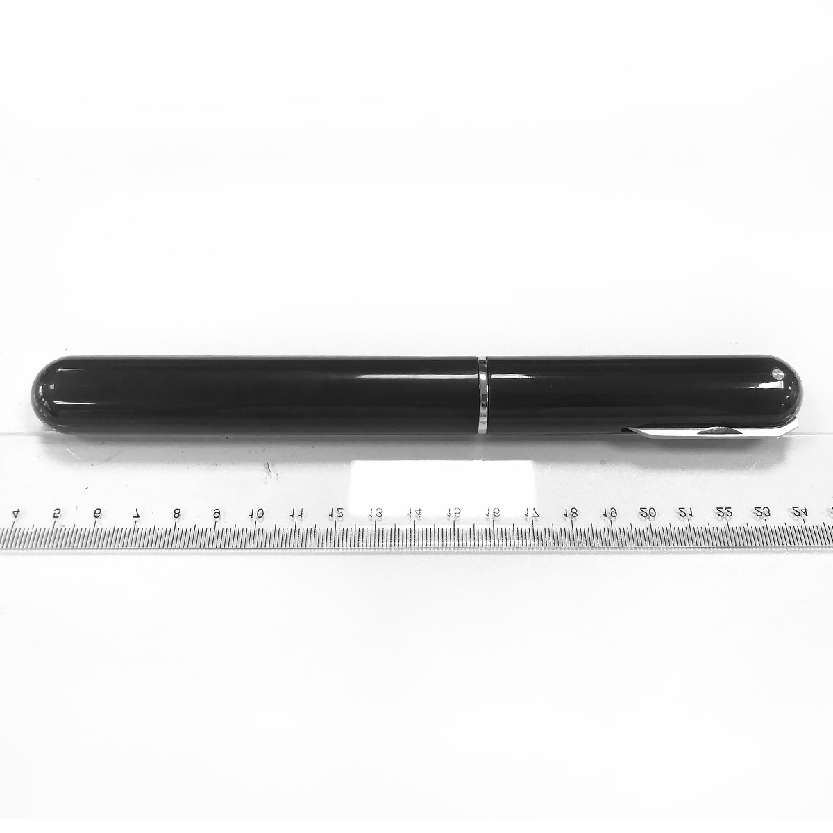 Ein schwarzer Stift liegt auf einem Lineal mit Markierungen von 1 bis 24.