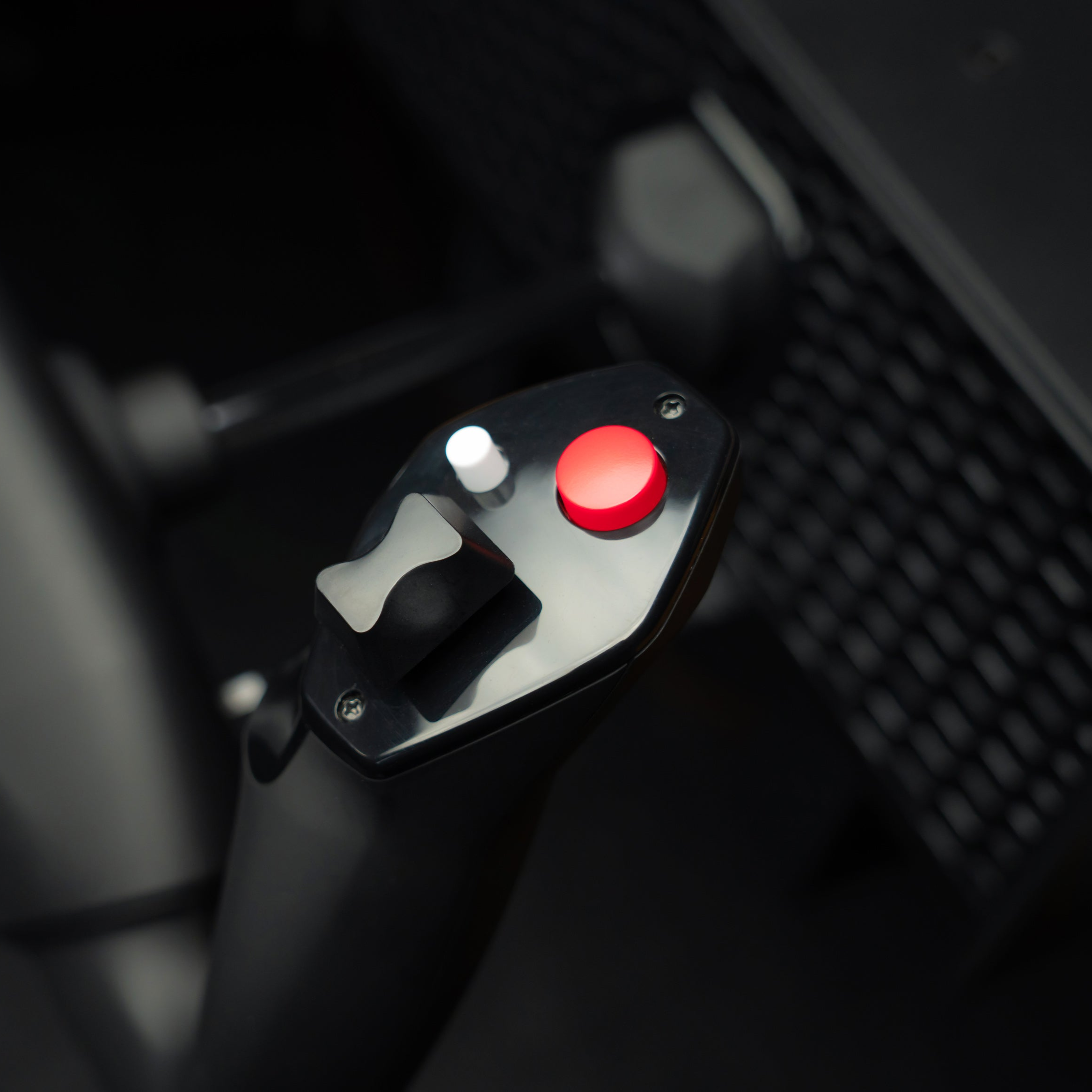 A black joystick with red and white buttons on a dark background.