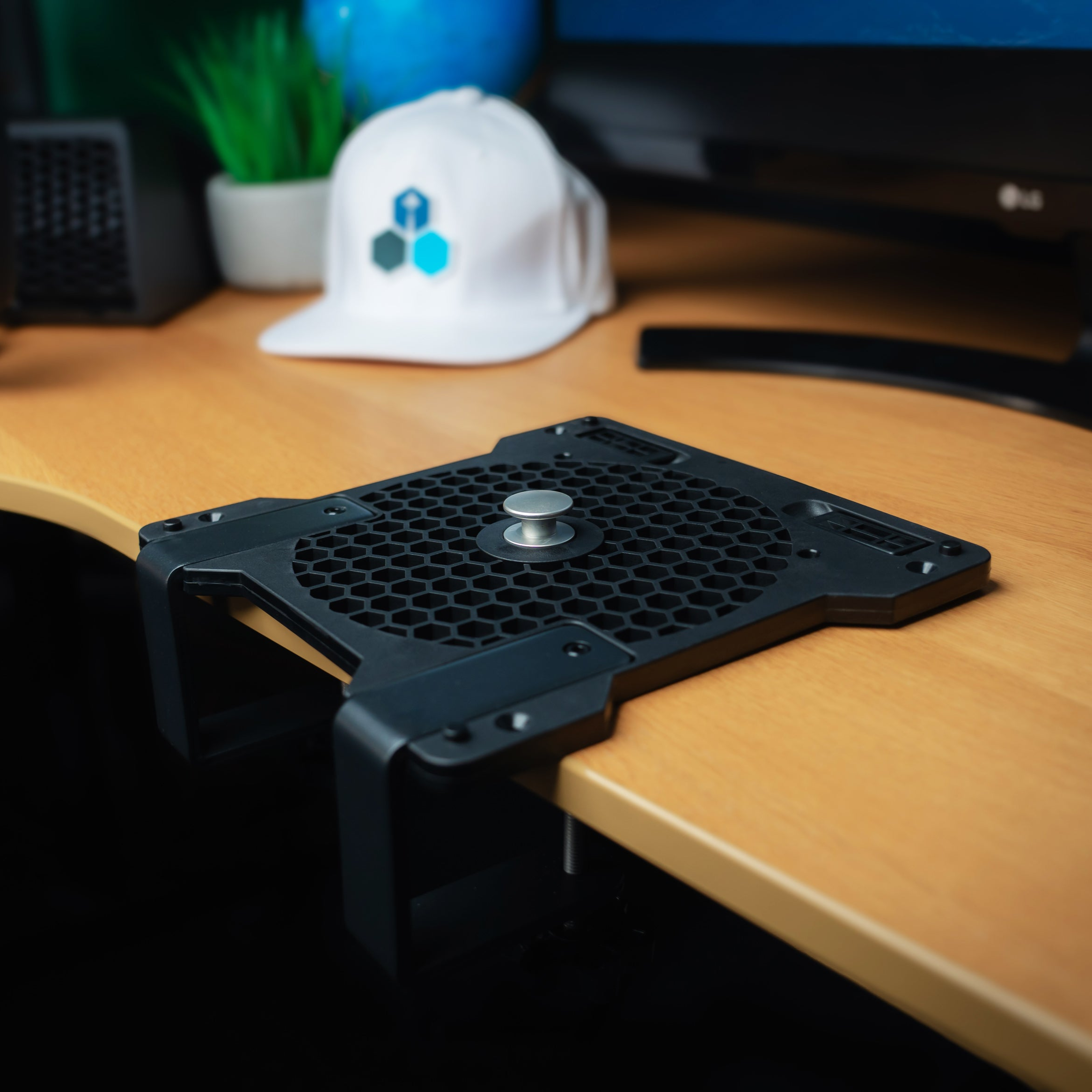 A black desk clamp mount with a hexagonal pattern and a silver knob.