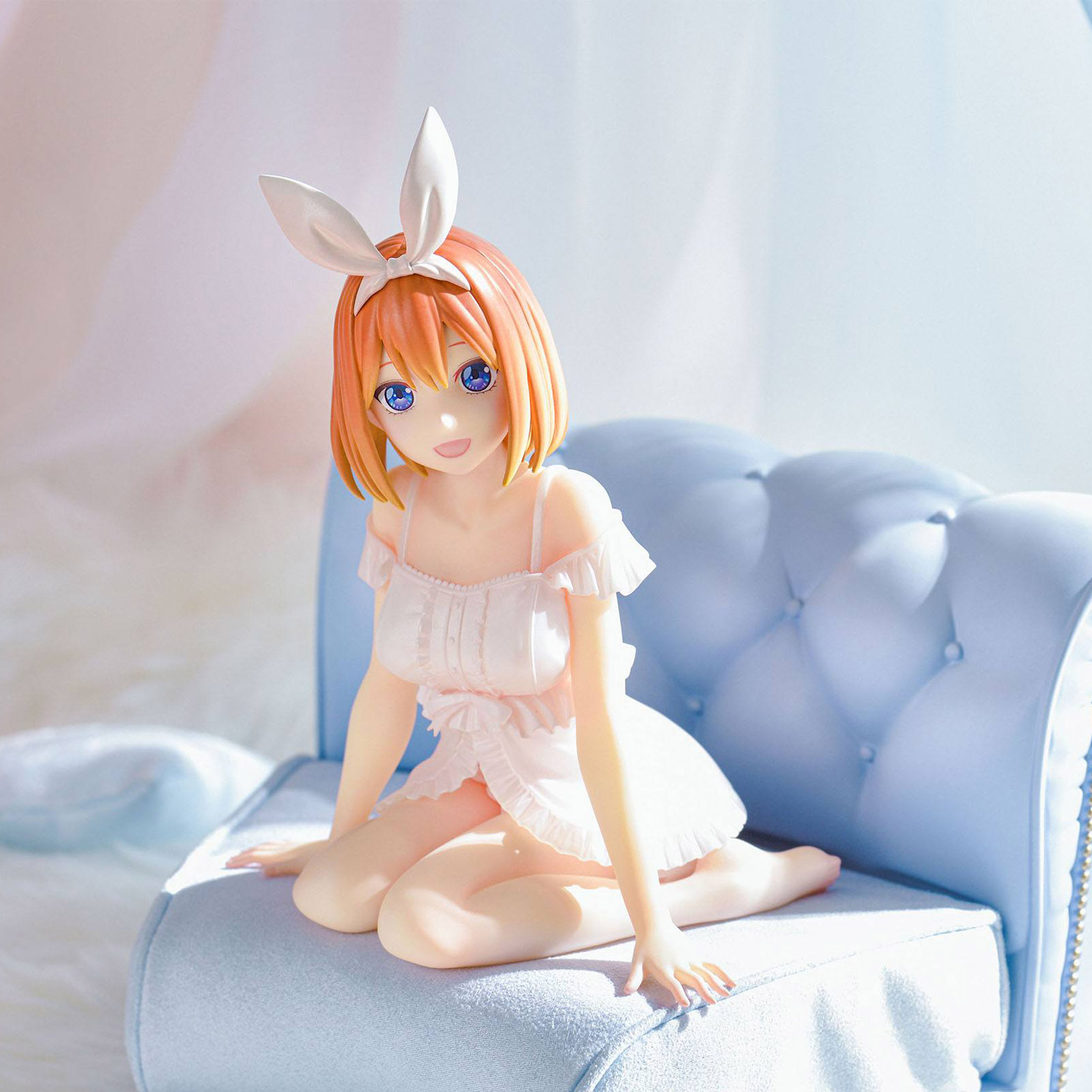 Eine Anime-Figur mit orangen Haaren und Hasenohren sitzt auf einem blauen Sofa.