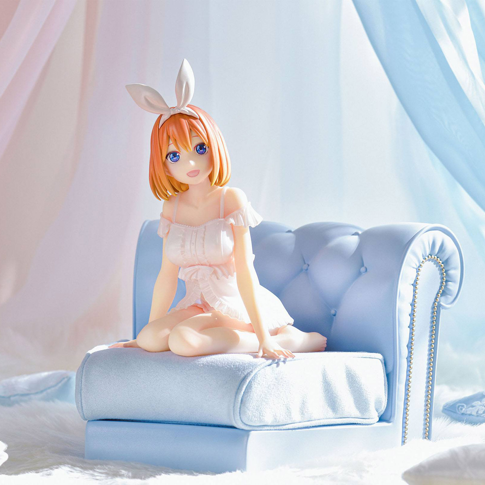 Eine Anime-Figur mit orangefarbenem Haar und Hasenohren sitzt auf einer blauen Couch.