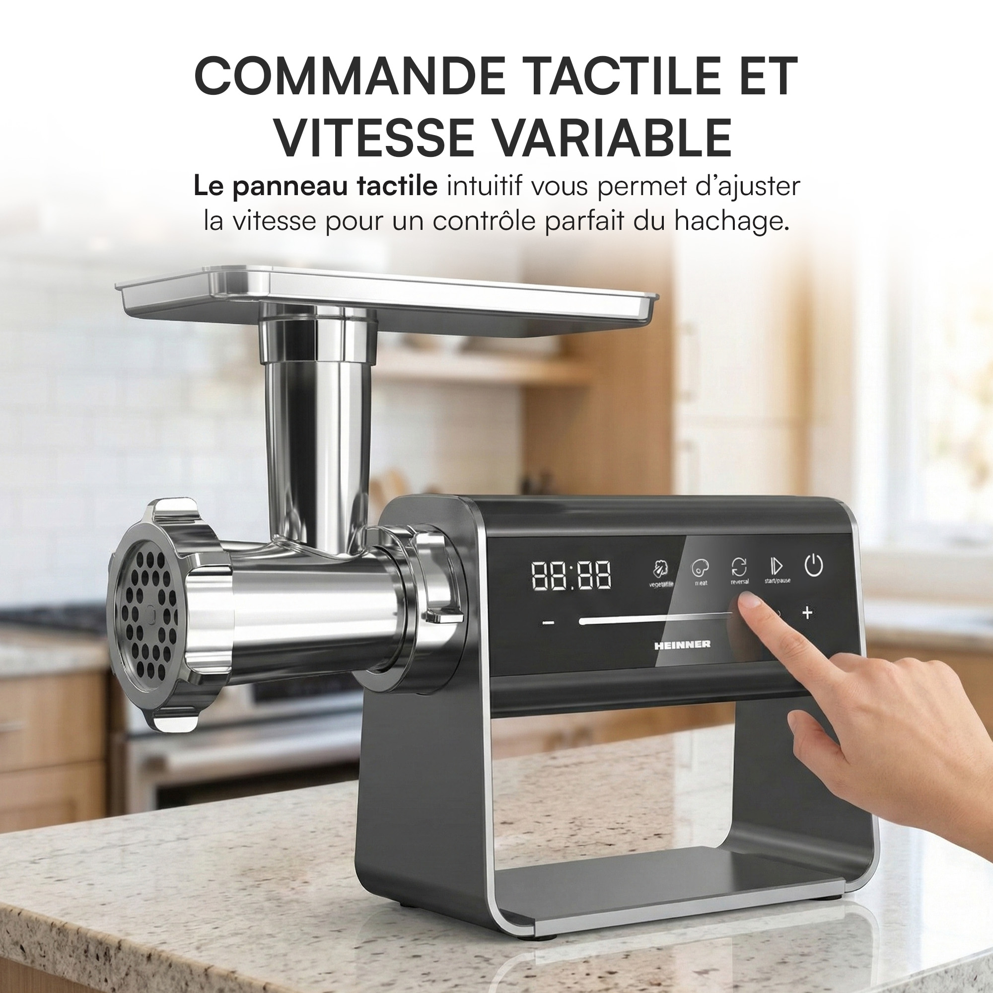 Un hachoir à viande avec écran tactile, une main appuie sur le bouton marche arrière.