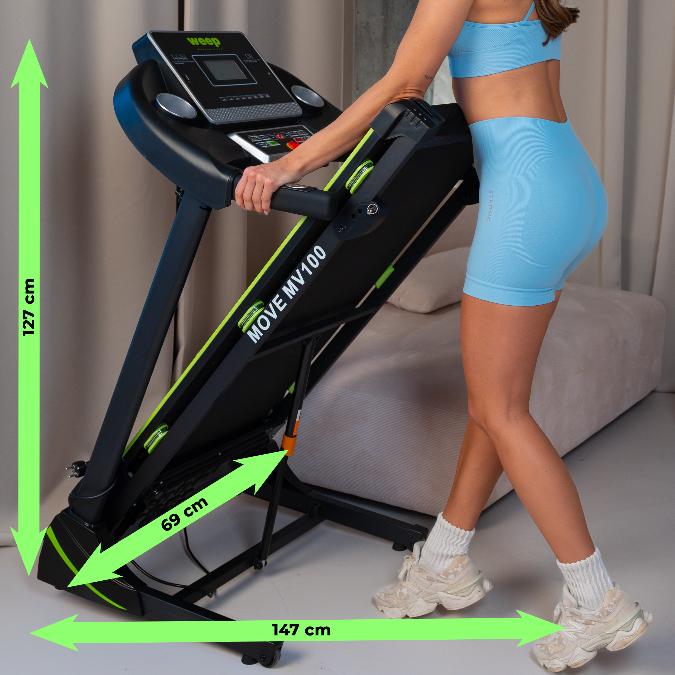 Kobieta w niebieskim stroju sportowym stoi obok bieżni. Podano wymiary.