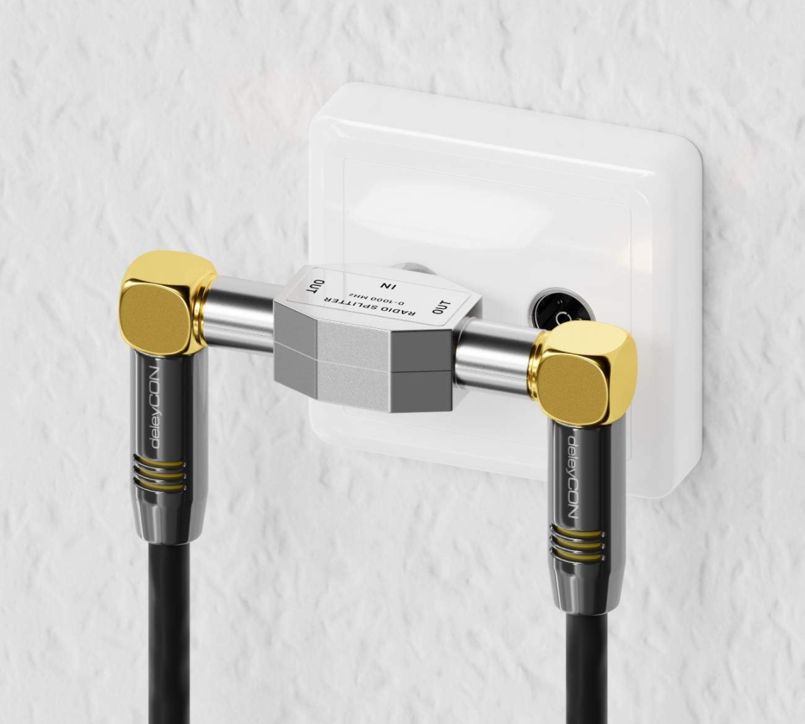 Un divisor de radio plateado con conectores dorados divide un cable en dos salidas.
