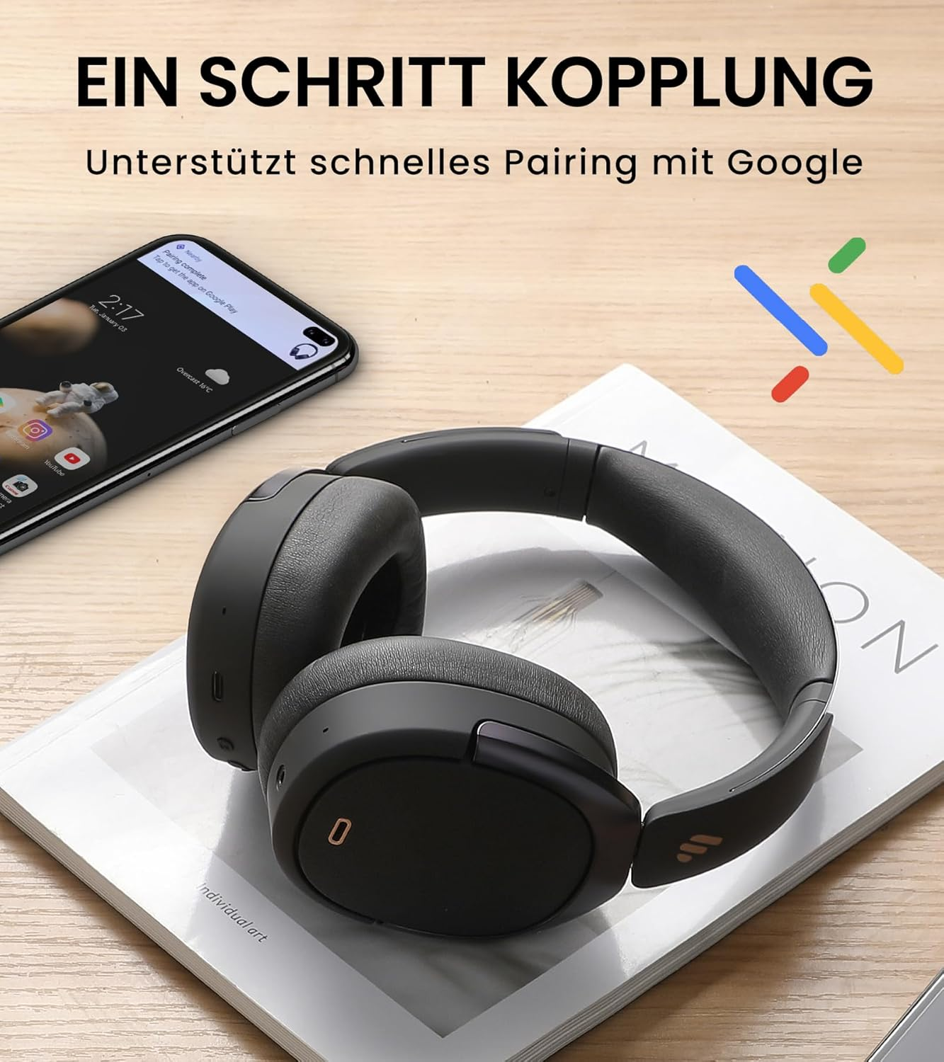Schwarze Kopfhörer liegen auf einem Buch neben einem Smartphone mit Benachrichtigung.