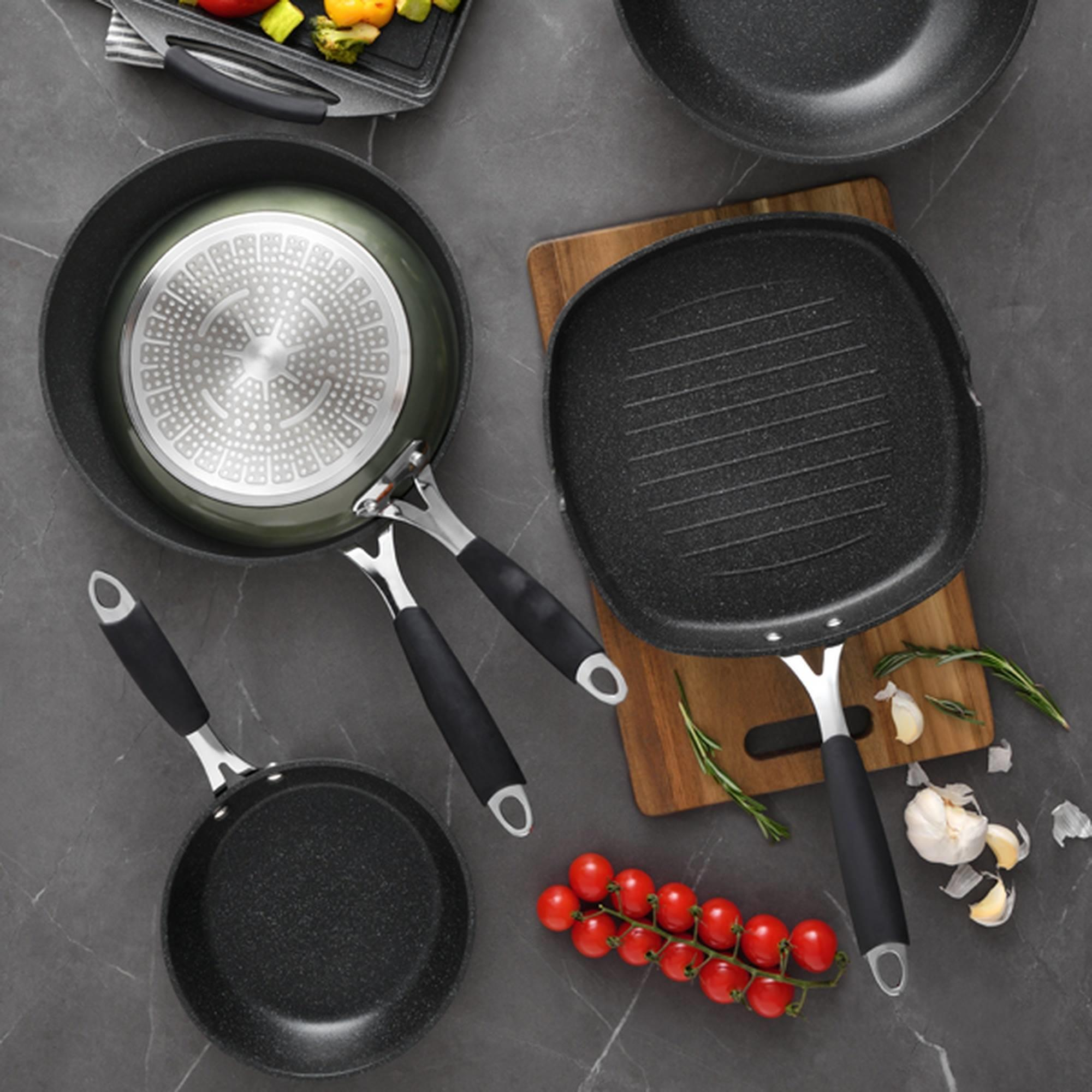 Utensilios de cocina con tomates cherry y ajo sobre mármol.