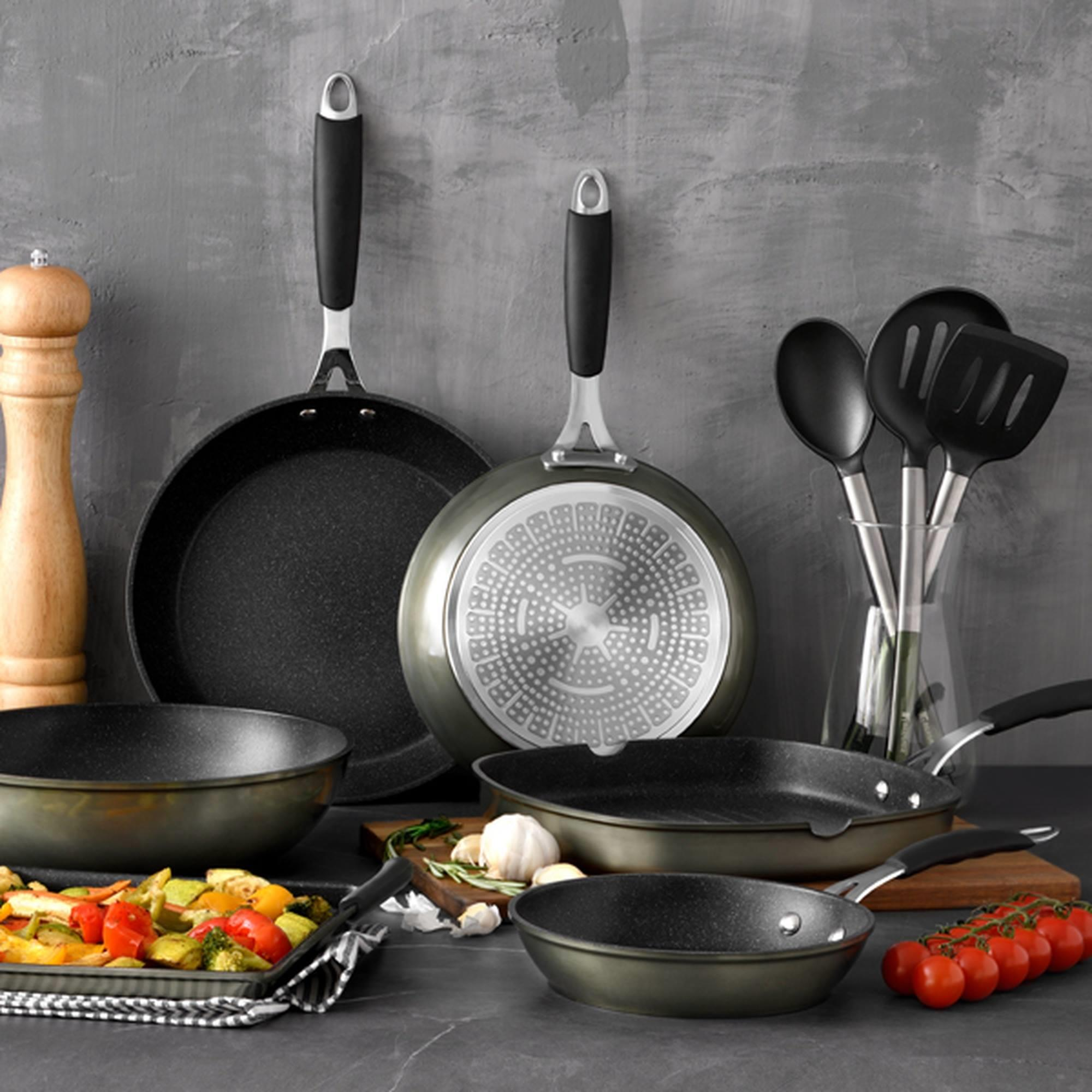Utensilios de cocina y verduras: sartenes, cucharas, molinillo, tomates.
