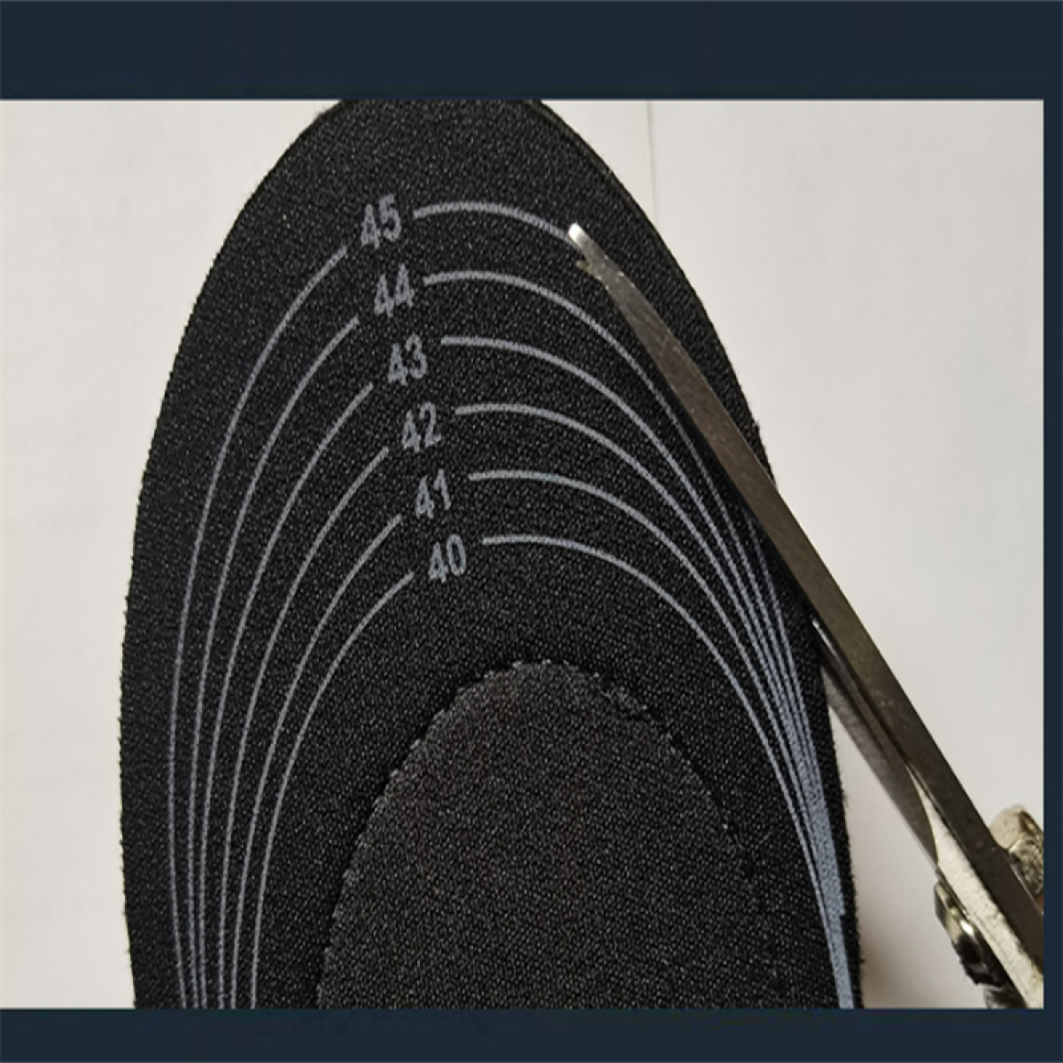 Nożyczki tną czarną wkładkę z oznaczeniami rozmiarów od 40 do 45.