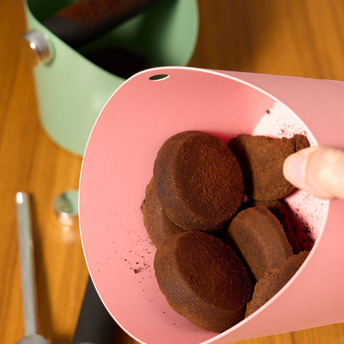 Ein rosafarbener Behälter mit Kaffeesatz, daneben ein hellgrüner Behälter.