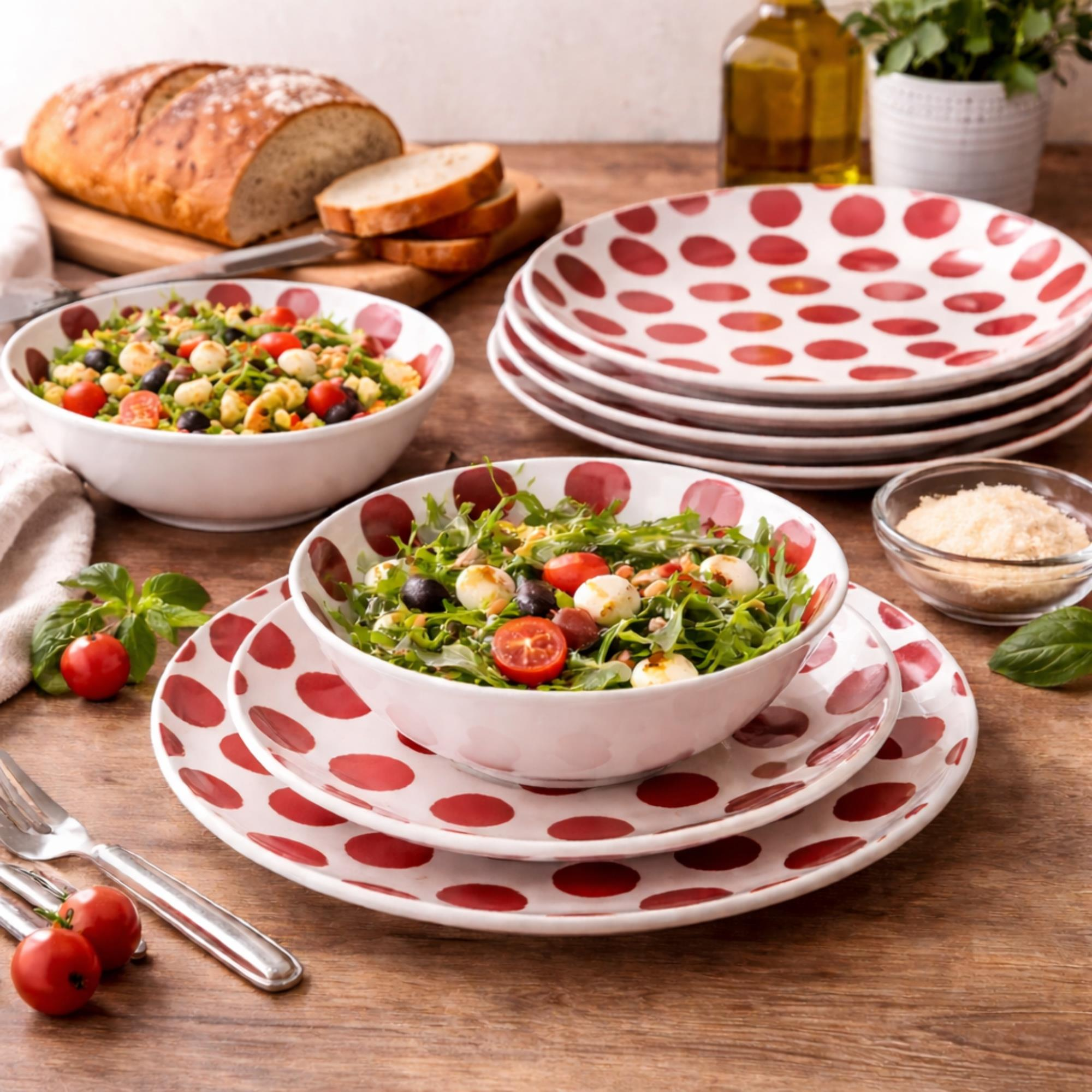 Ensalada en cuenco de lunares rojos, con pan, aceite y queso cerca.