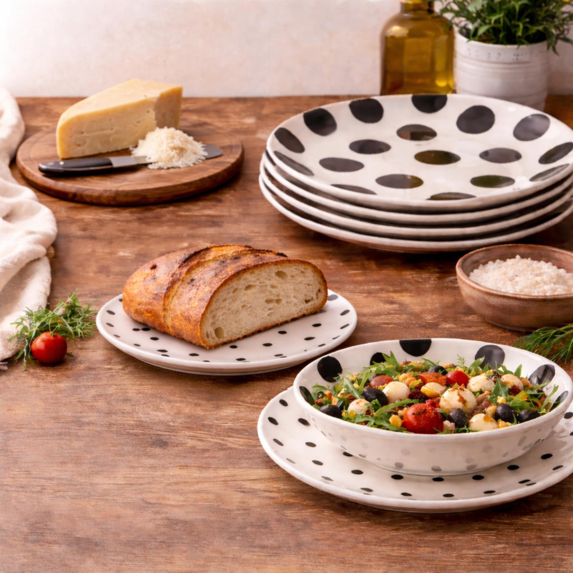 Un ajuste de mesa rústico con queso, pan y ensalada en platos de lunares.