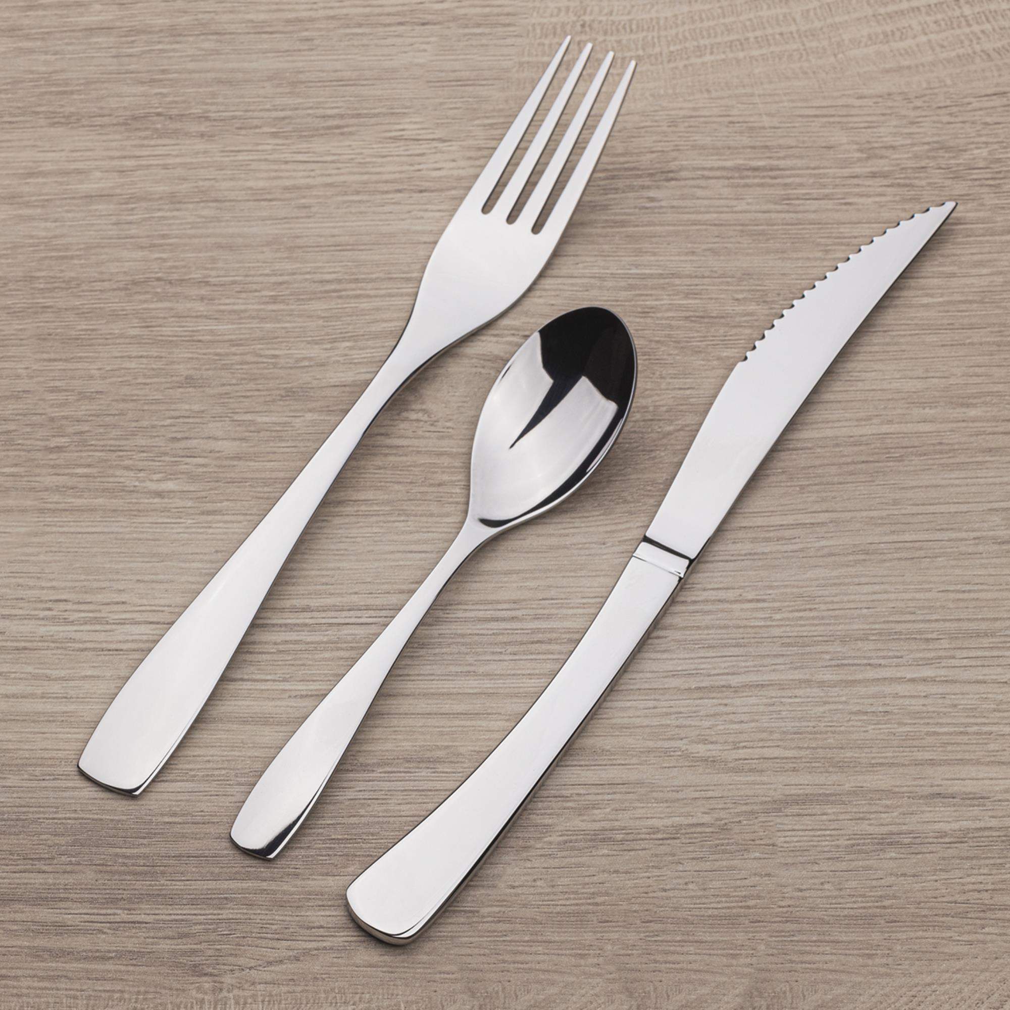 Una cuchara, tenedor y cuchillo plateados sobre una superficie de madera.