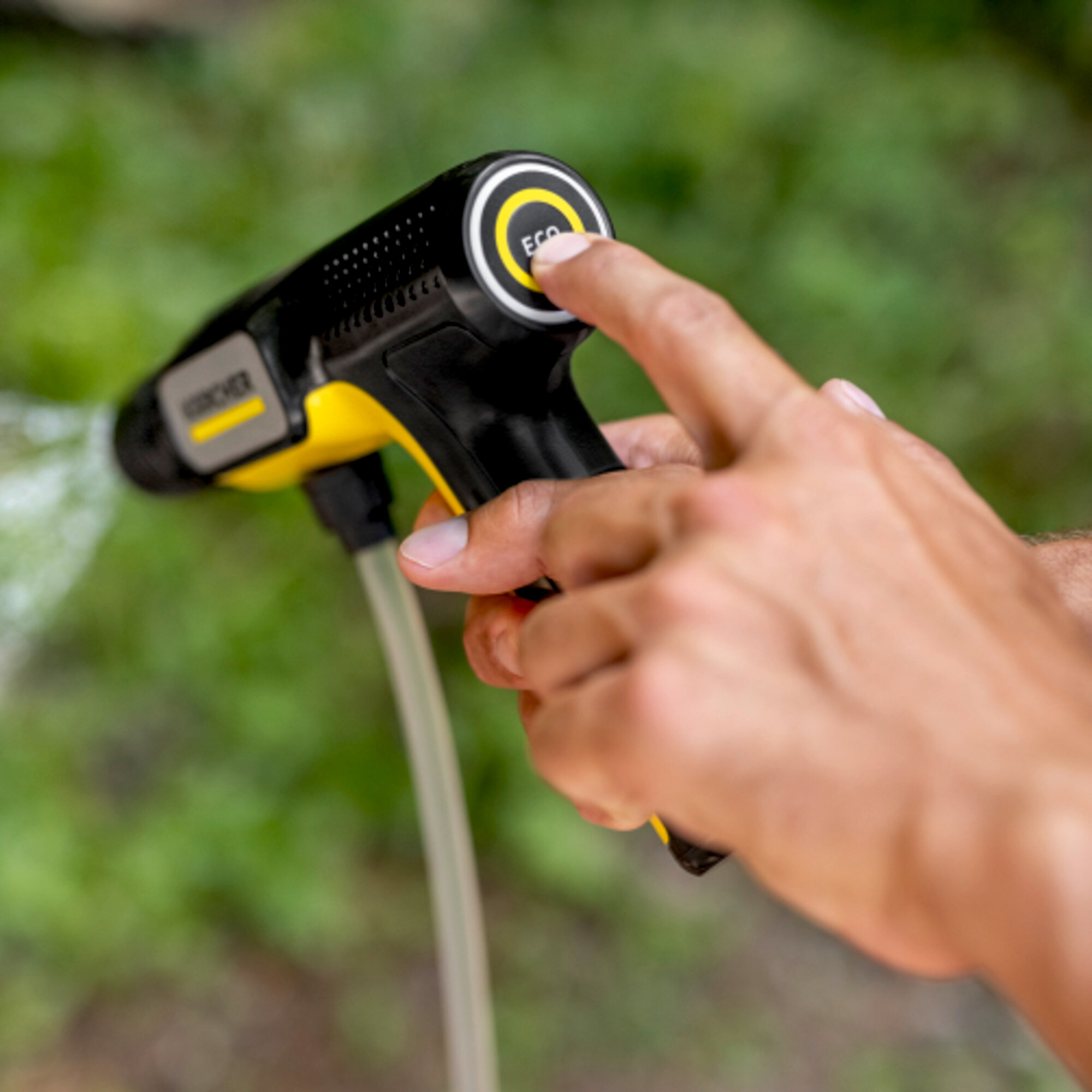 Eine Hand drückt den ECO-Knopf einer schwarzen und gelben Spritzpistole mit Wasserstrahl.