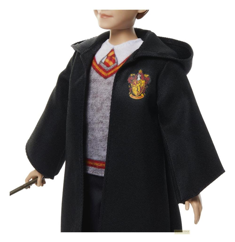 Ein Mann trägt einen schwarzen Umhang über einem grauen Pullover, weißem Hemd und Krawatte.