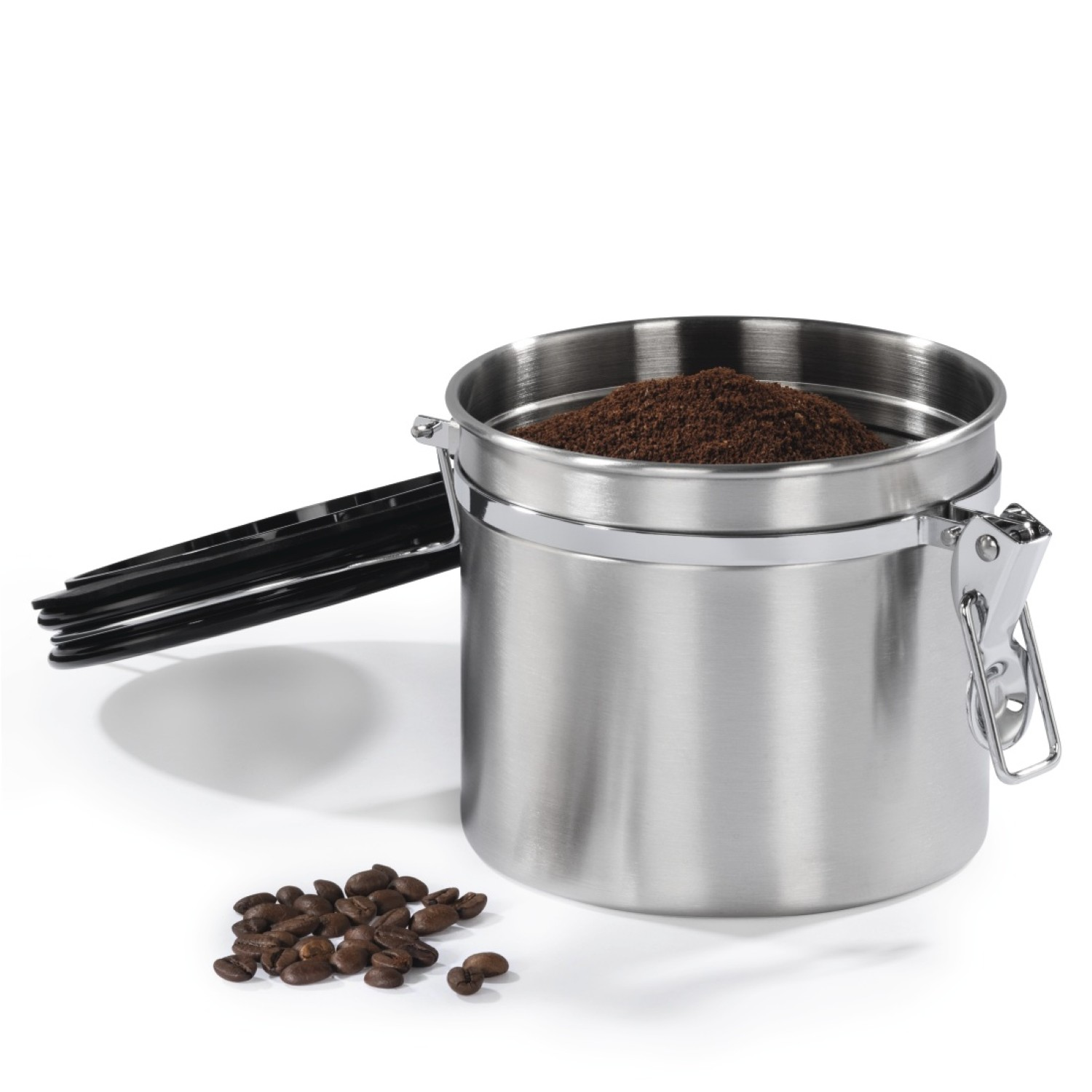 Edelstahlbehälter mit schwarzem Griff und Kaffeepulver, daneben Kaffeebohnen.