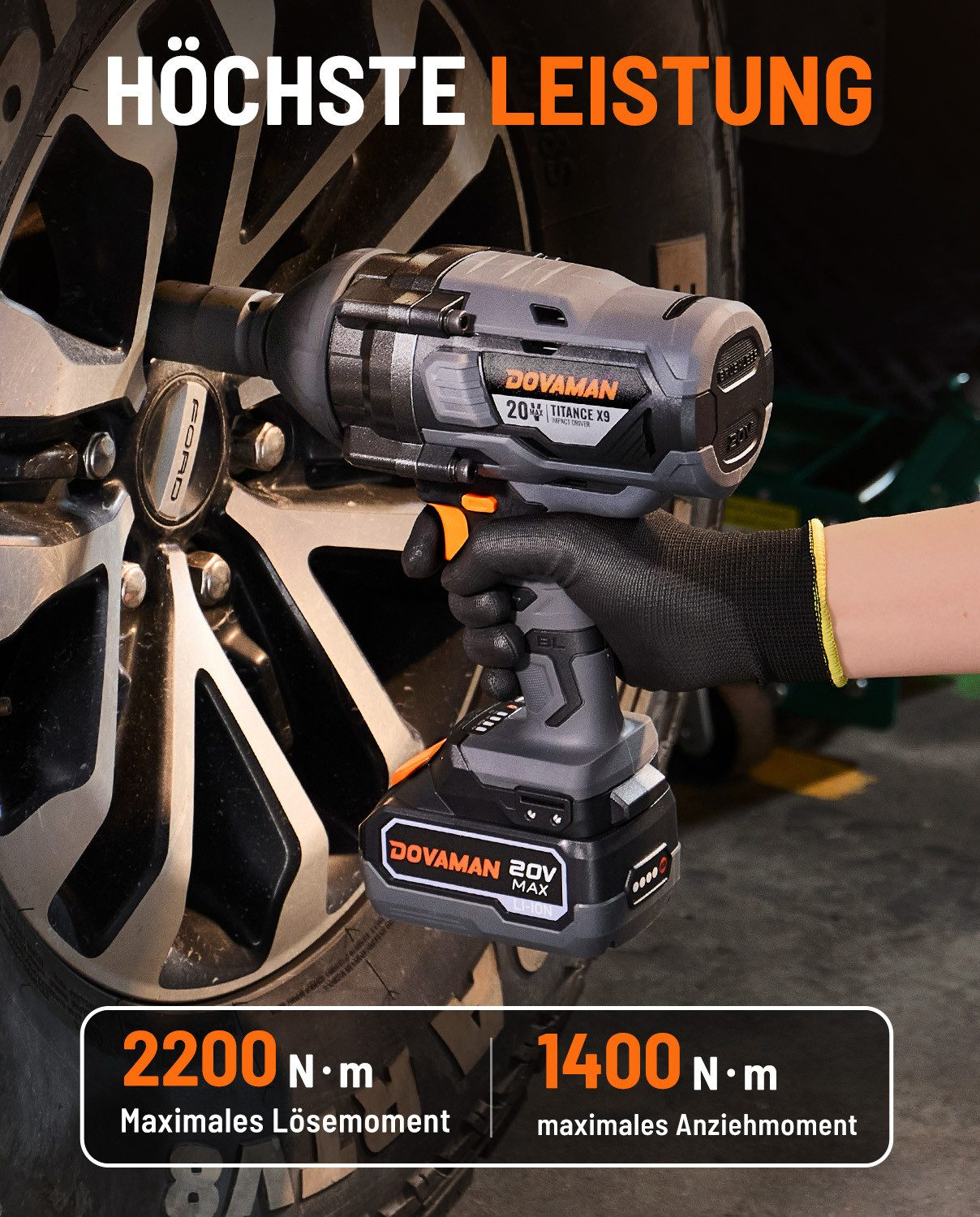 Ein schwarzer Handschuh hält einen grauen und orangen Schlagschrauber nahe einem Autorad.