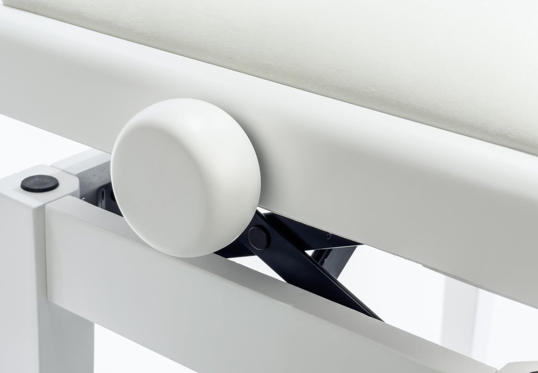 Detailaufnahme einer weißen Tischplatte mit schwarzem Mechanismus und rundem Knopf.
