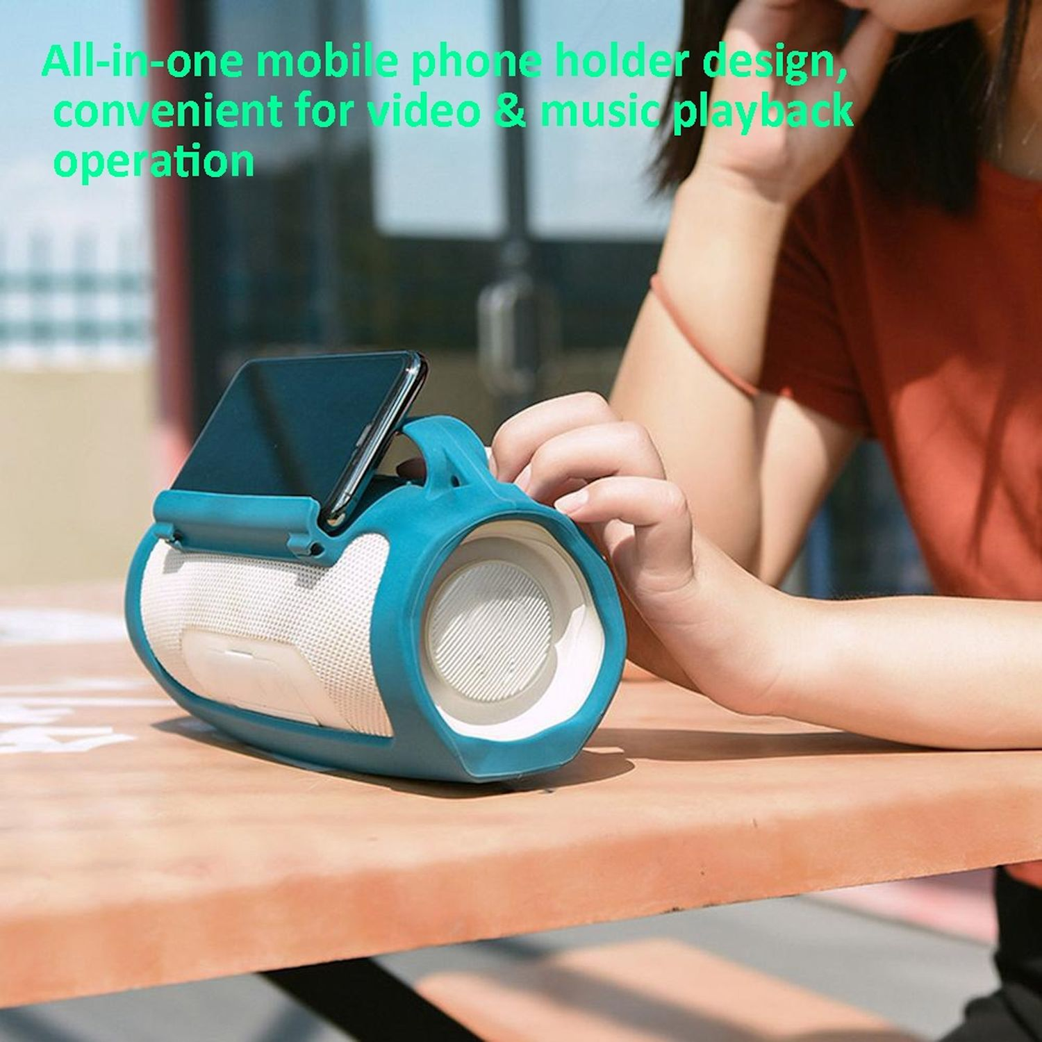 Un altavoz portátil azul con soporte para teléfono en una mesa.