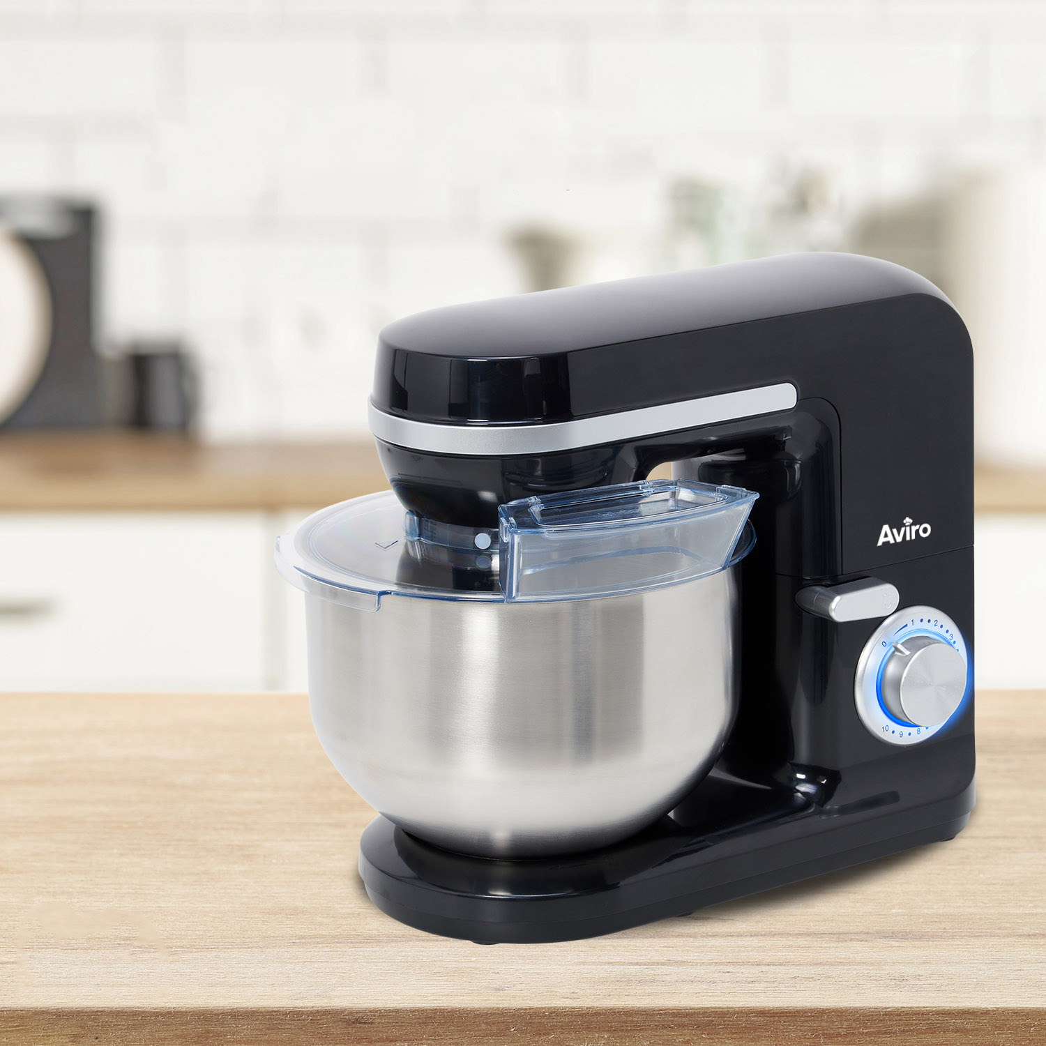Black stand mixer with stainless steel bowl on a wooden table.
