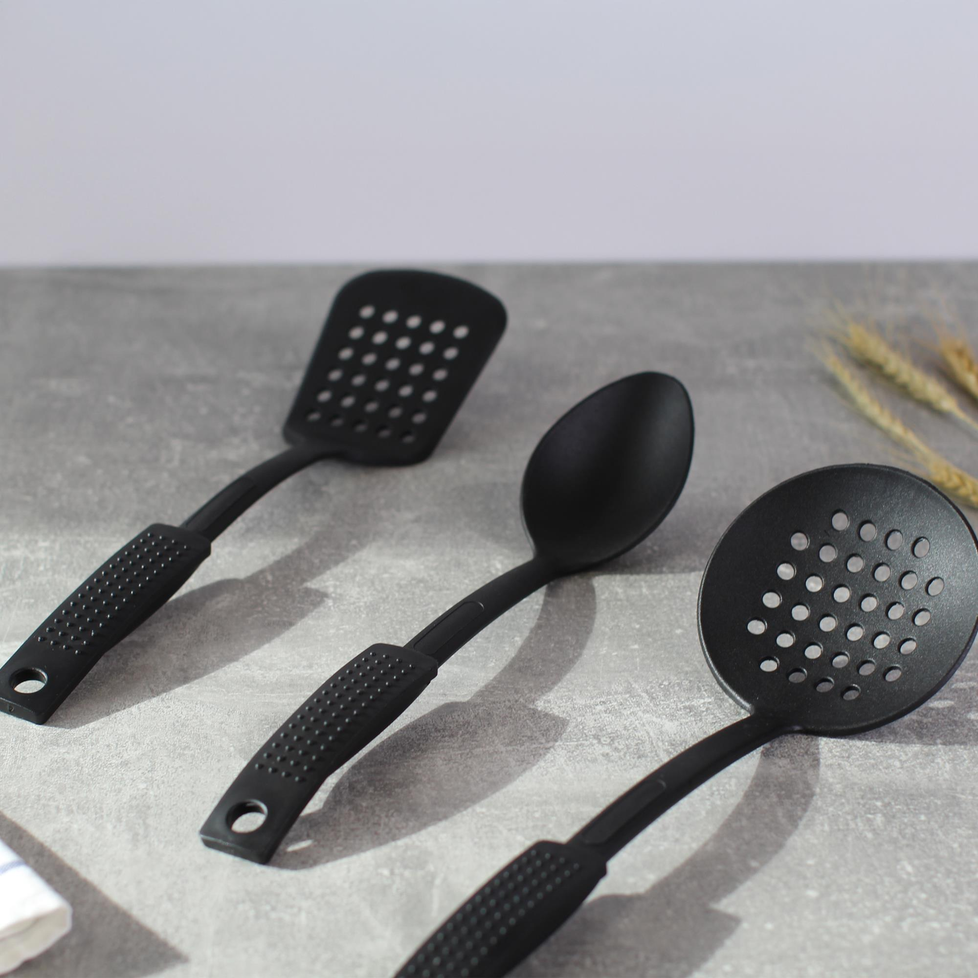 Tres utensilios de cocina negros: espumadera, espátula y cuchara.