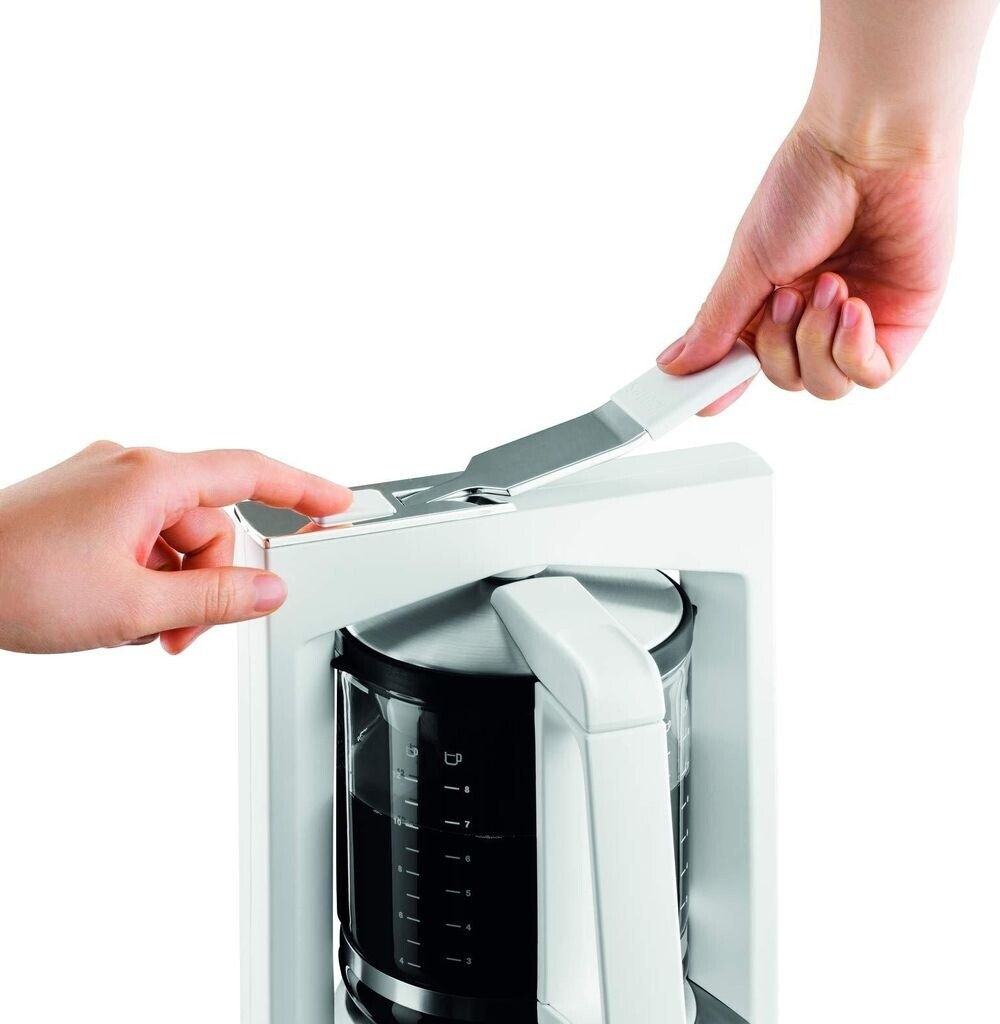 Dłonie obsługujące biały ekspres do kawy ze szklanym dzbankiem i podziałką.