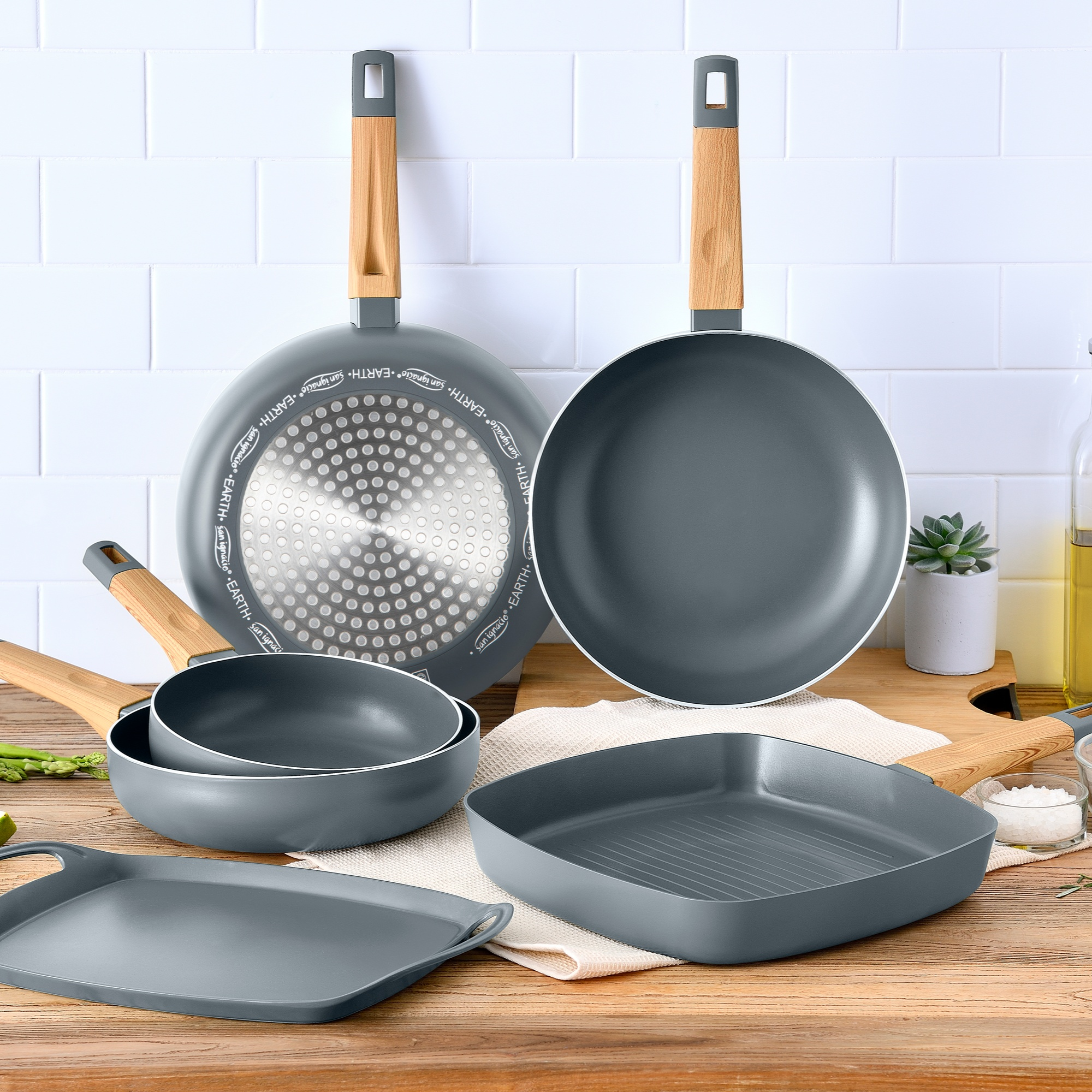 Utensilios de cocina grises con mangos de madera sobre una mesa de madera.