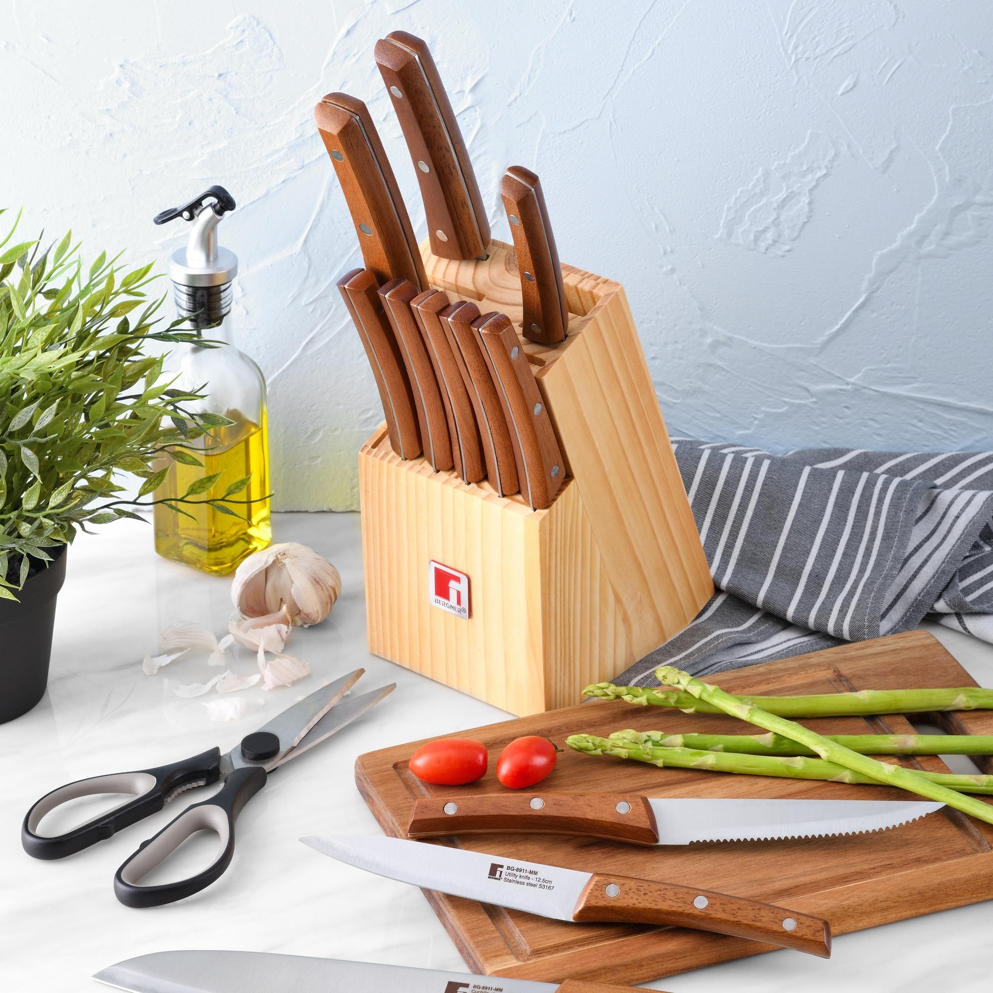 Bloque de cuchillos de madera con cuchillos, dispensador, ajo, tomates, espárragos.
