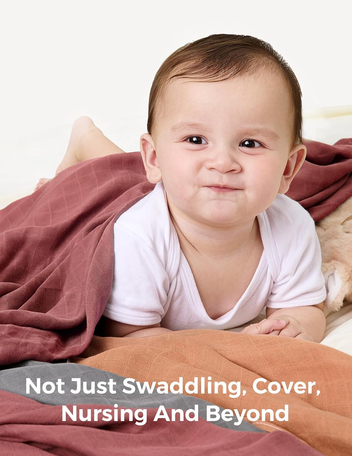 Un bambino giace su coperte colorate, indossa una tutina bianca.