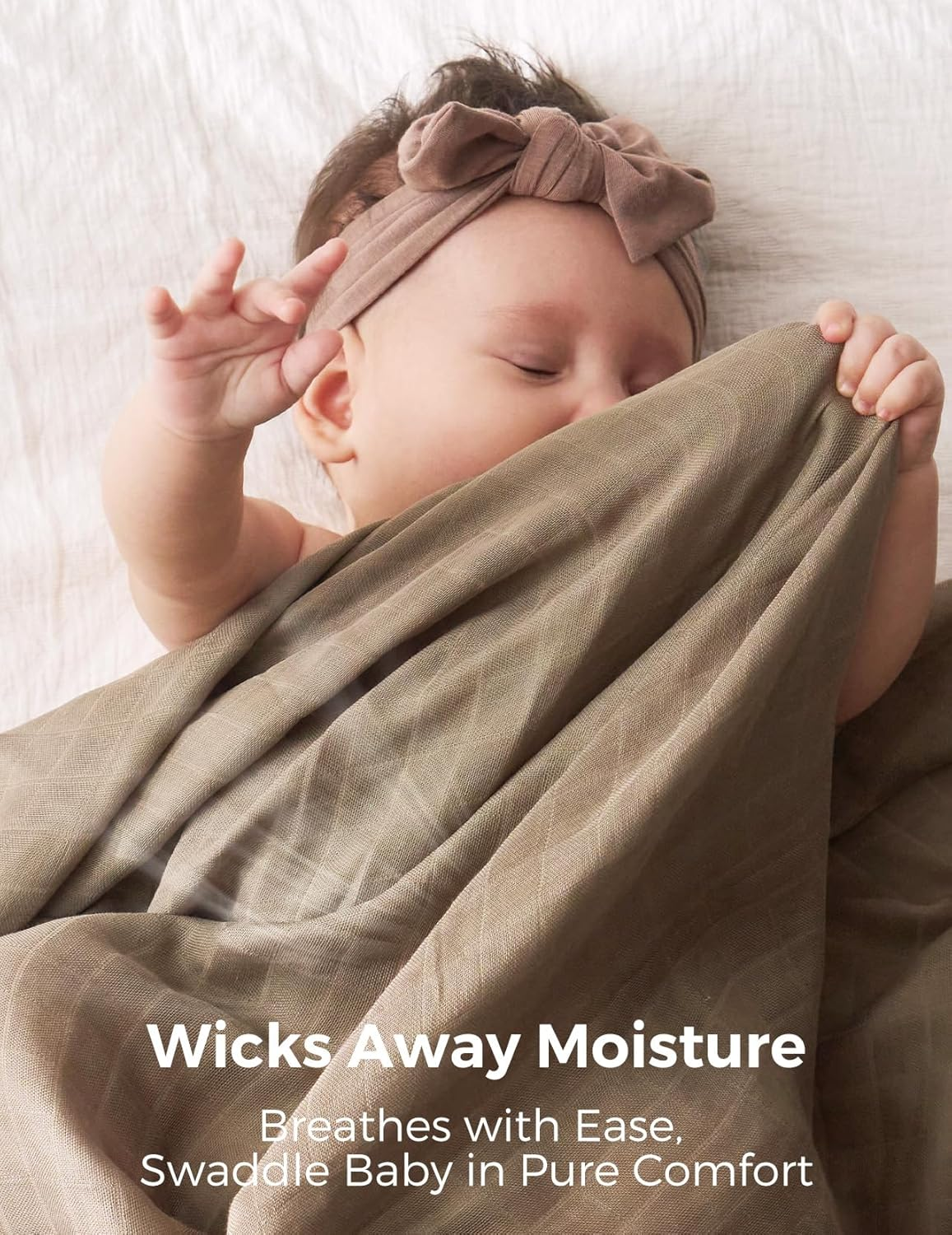 Bambino con fascia marrone dorme su coperta bianca, coperto da stoffa marrone.