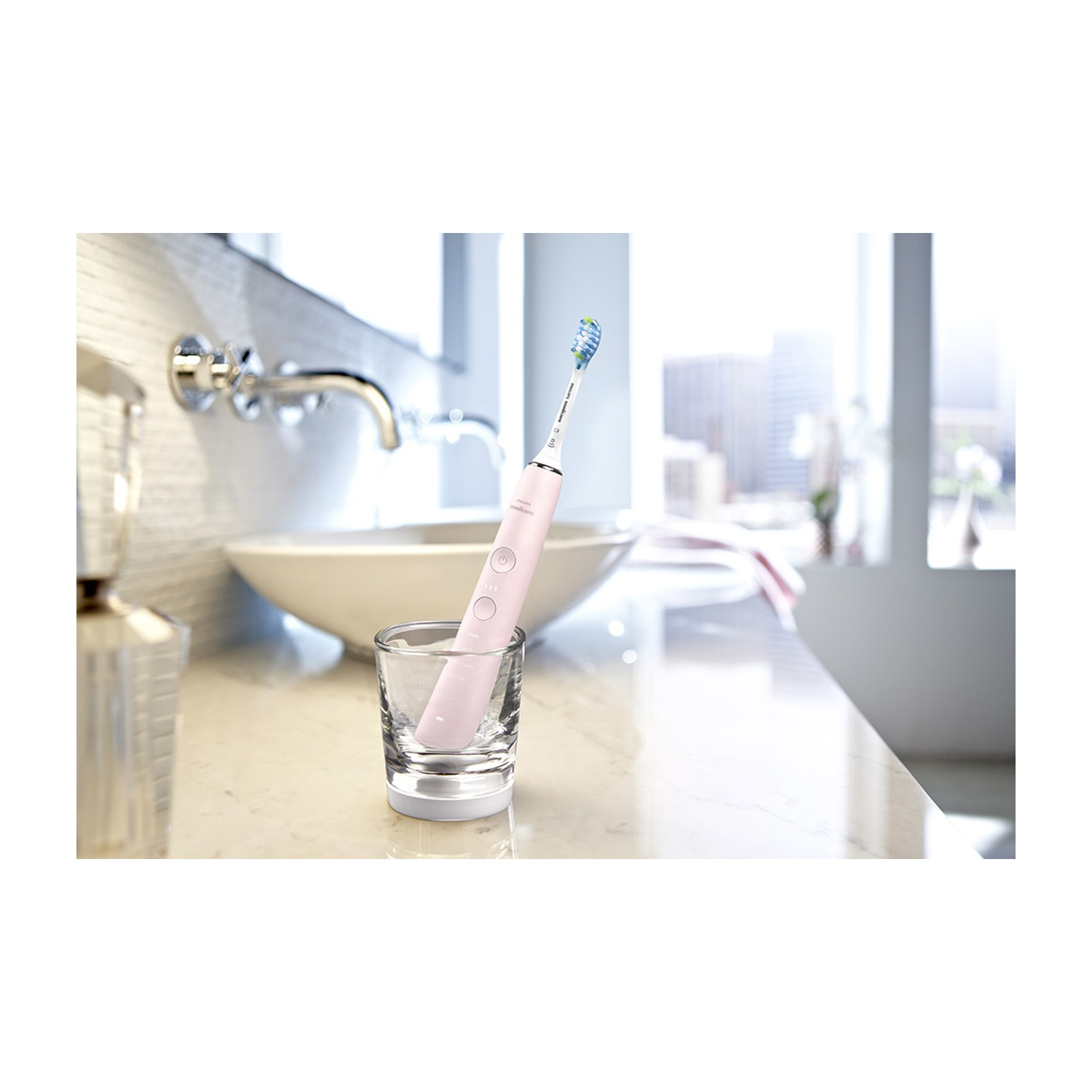 Un cepillo de dientes eléctrico rosa está en un vaso sobre una encimera.