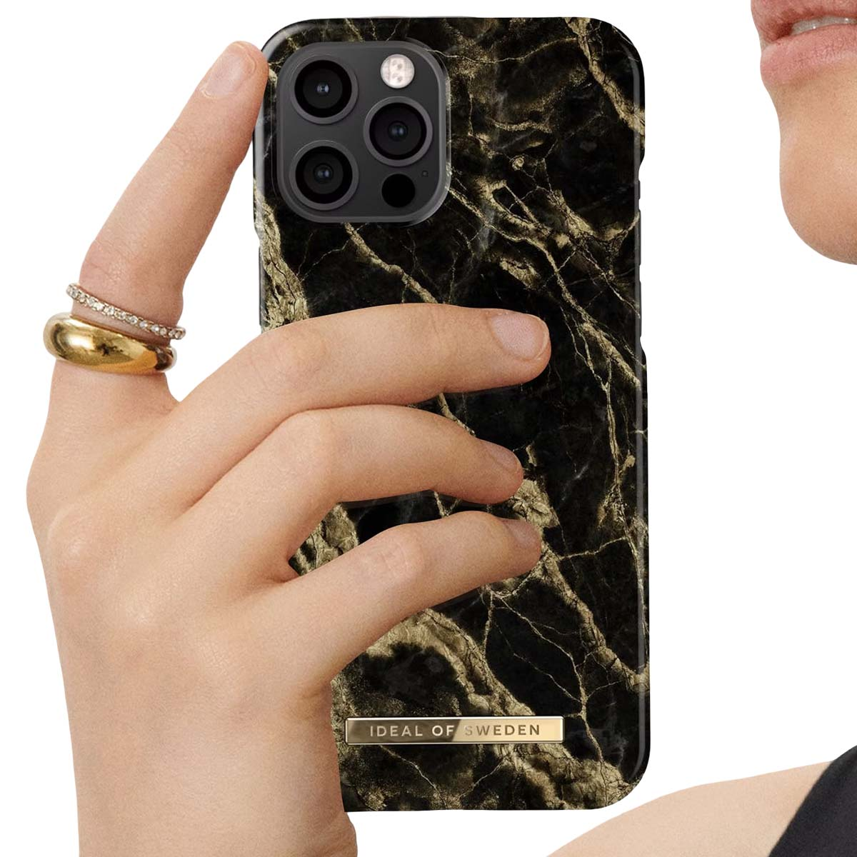 Eine Hand mit Ringen hält eine schwarze Marmor-iPhone-Hülle mit Goldakzenten.