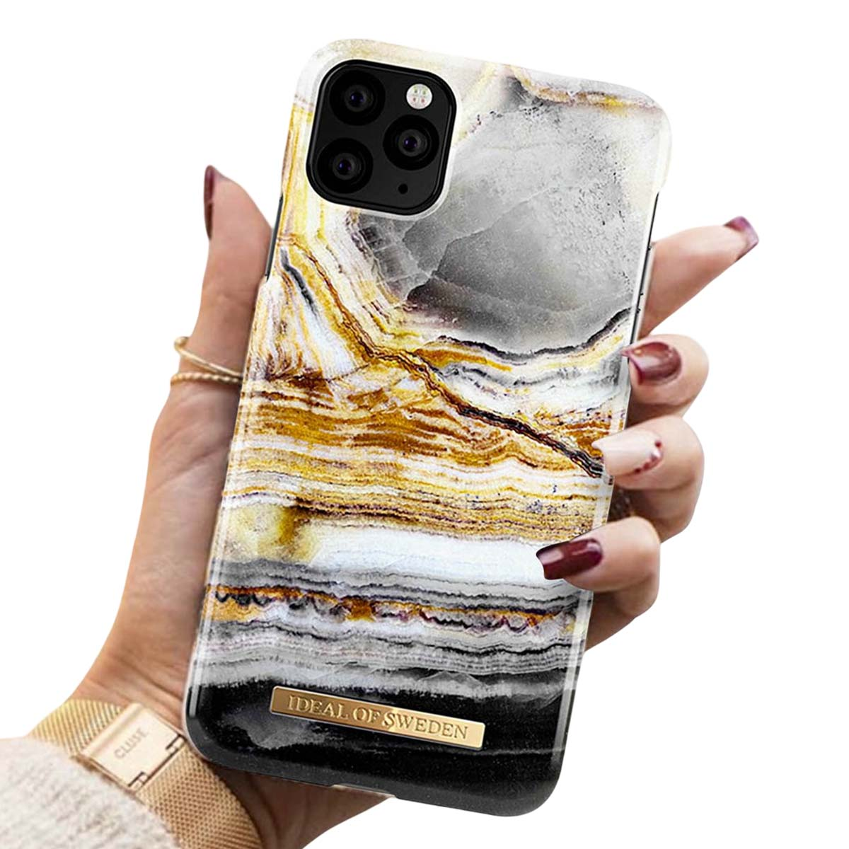 Una mano tiene una custodia per iPhone con motivo marmorizzato oro e bianco.