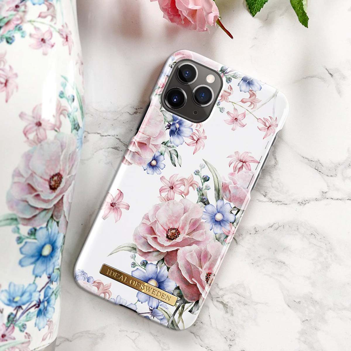 Un iPhone con una fantasia floreale di fiori rosa e blu su sfondo bianco.