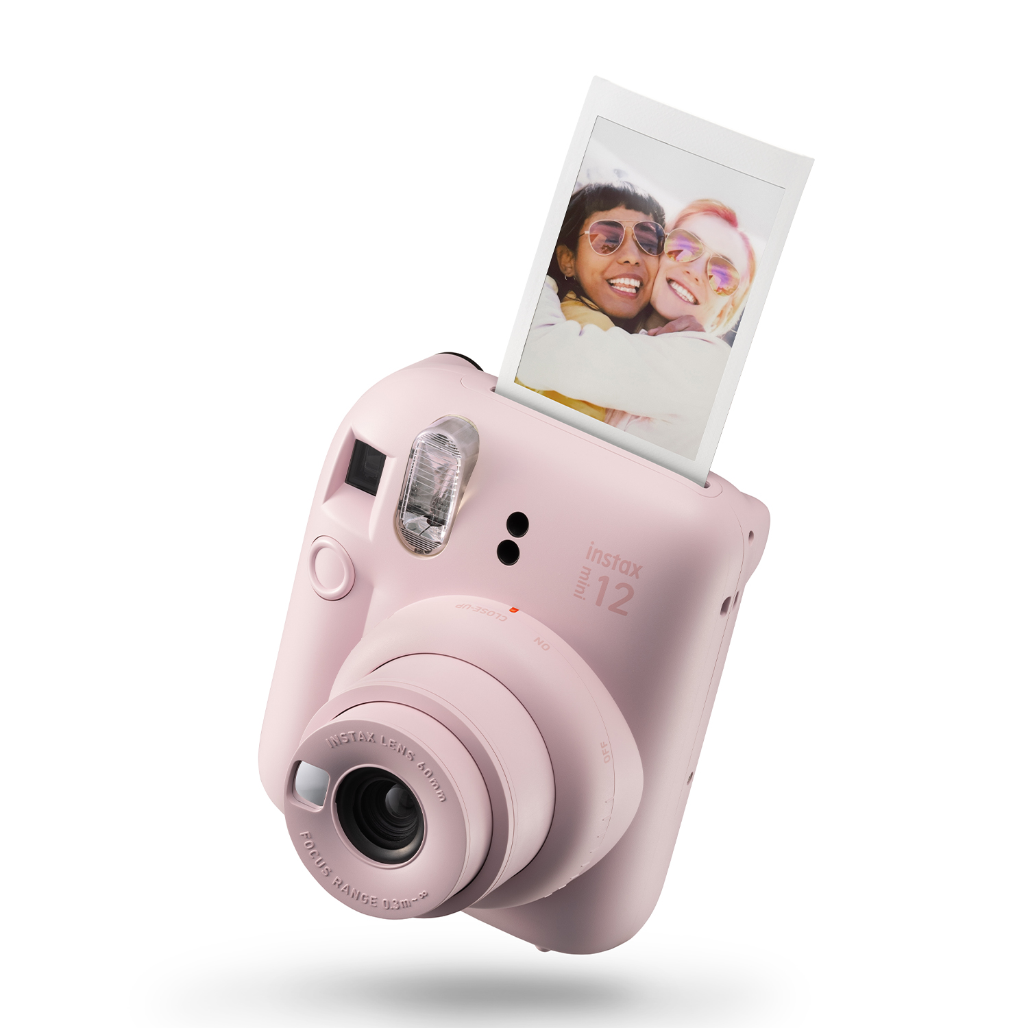 Różowy aparat Instax Mini 12 ze zdjęciem dwóch uśmiechniętych kobiet wychodzącym z góry.