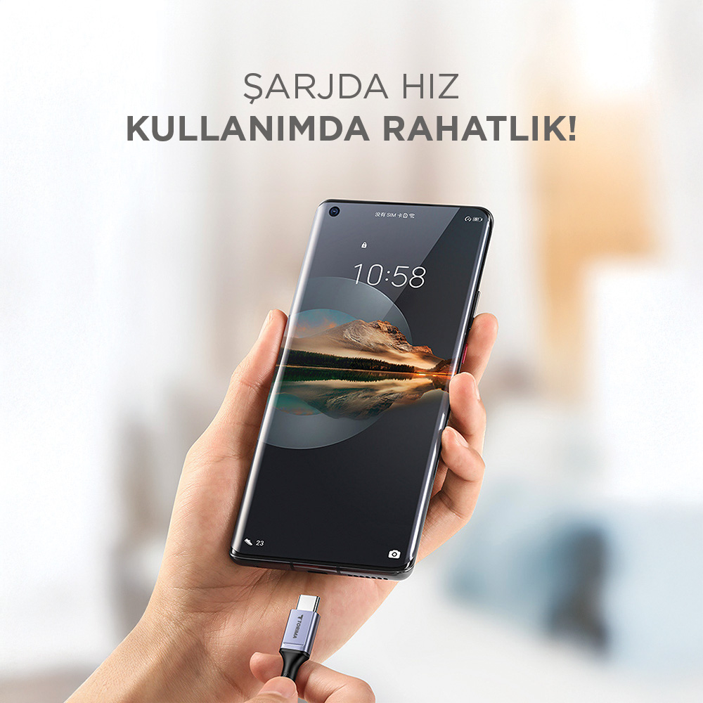 El, şarj kablosu takılı bir akıllı telefon tutuyor.