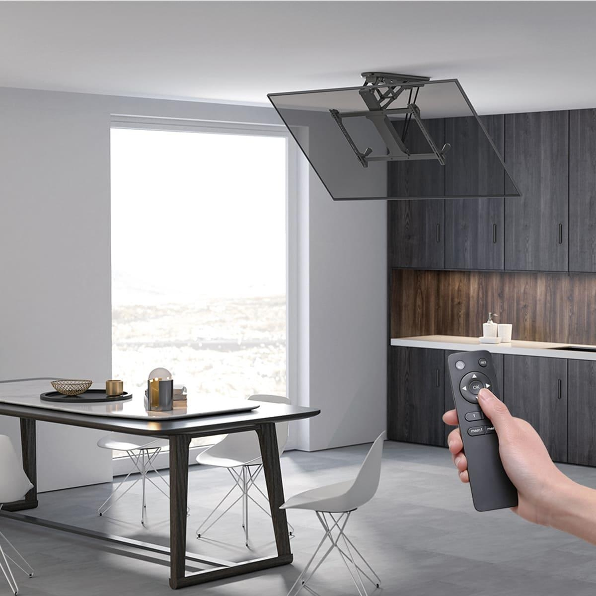 Eine Hand hält eine Fernbedienung vor einem ausfahrbaren Deckenfernseher in einem modernen Esszimmer.