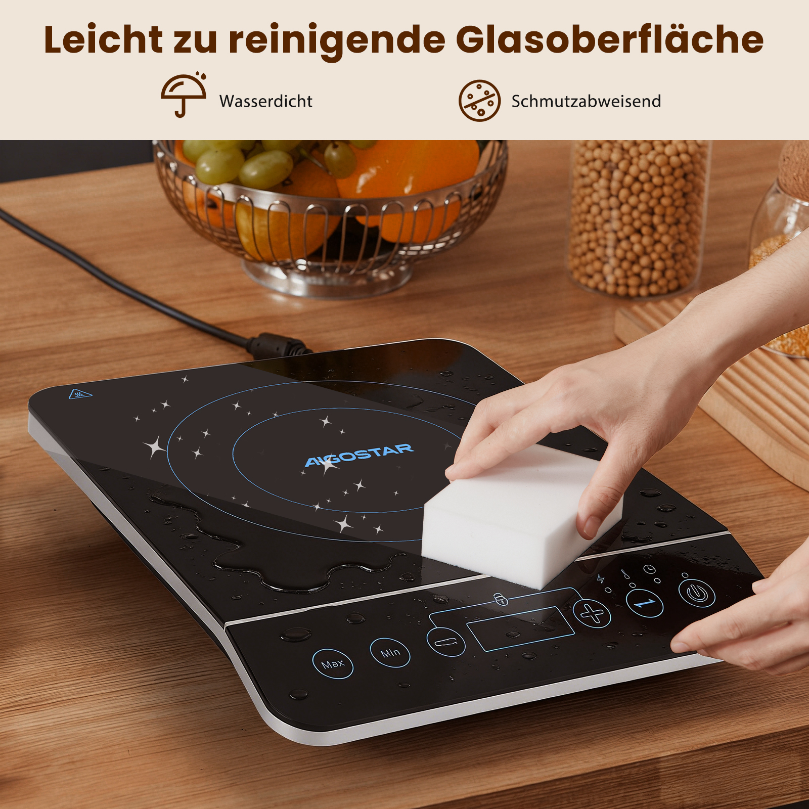 Eine Hand wischt mit einem weißen Schwamm über eine nasse schwarze Kochplatte.