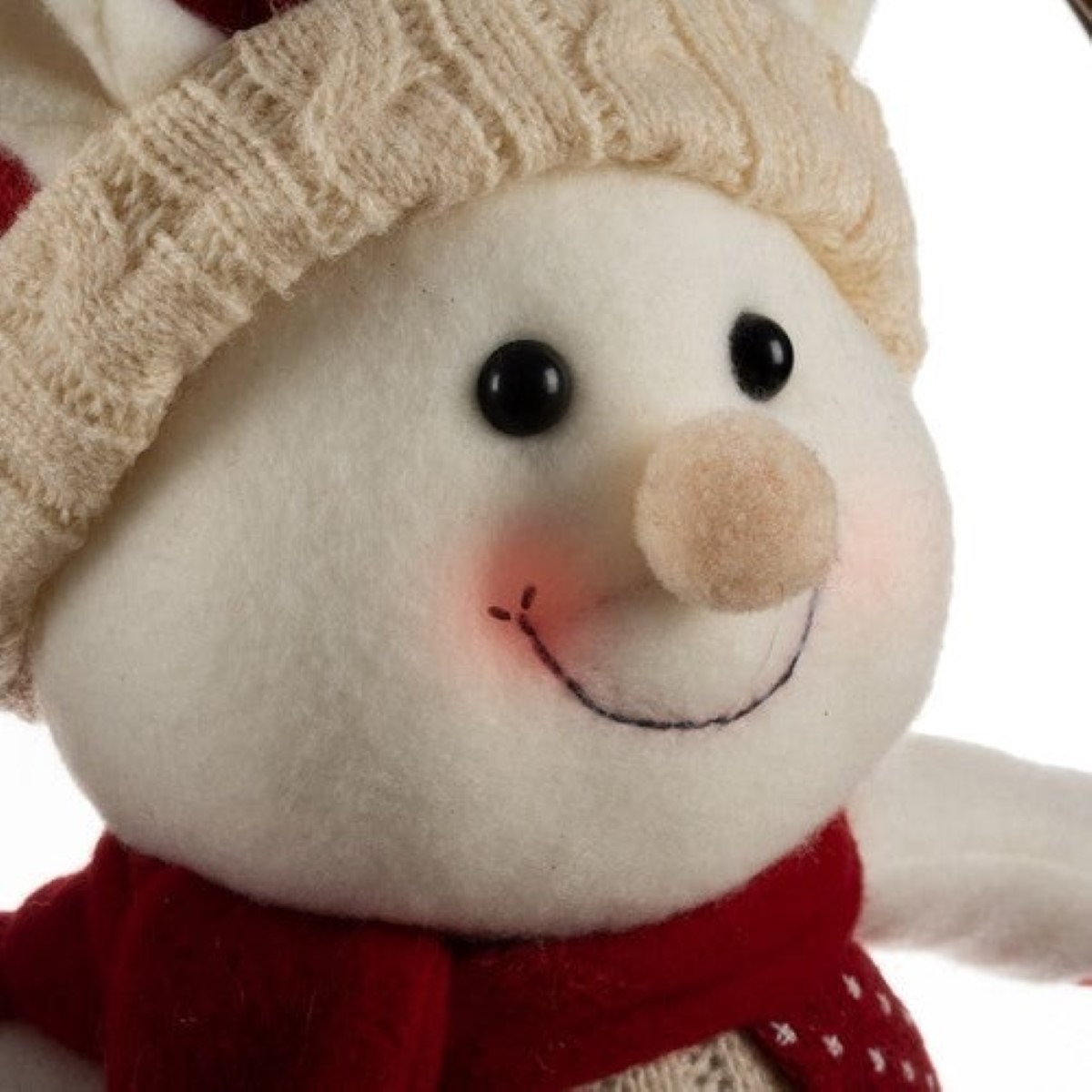 Un muñeco de nieve de peluche con gorro y bufanda roja.