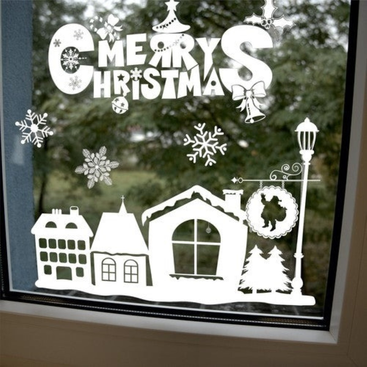 Weiße Weihnachtsaufkleber auf Fenster: Frohe Weihnachten Schriftzug, Schnee, Häuser, Nikolaus.