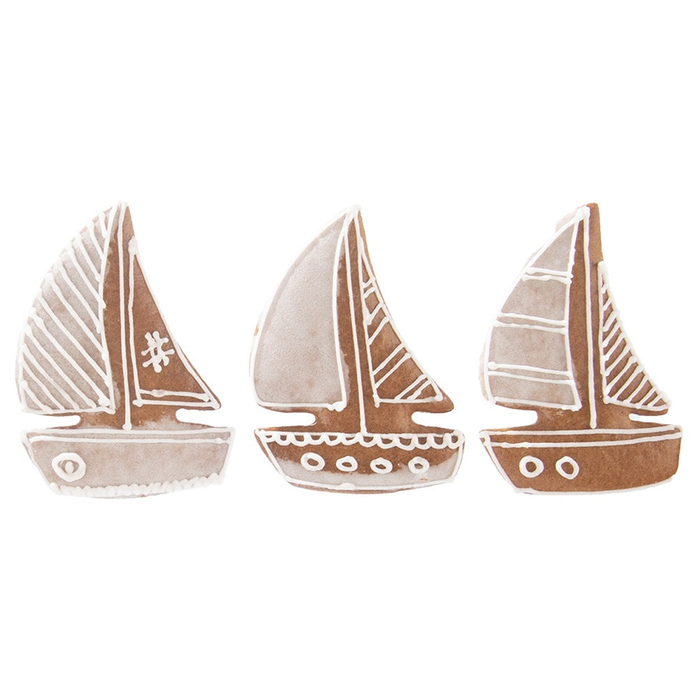 Tres galletas con forma de velero decoradas con glaseado blanco.