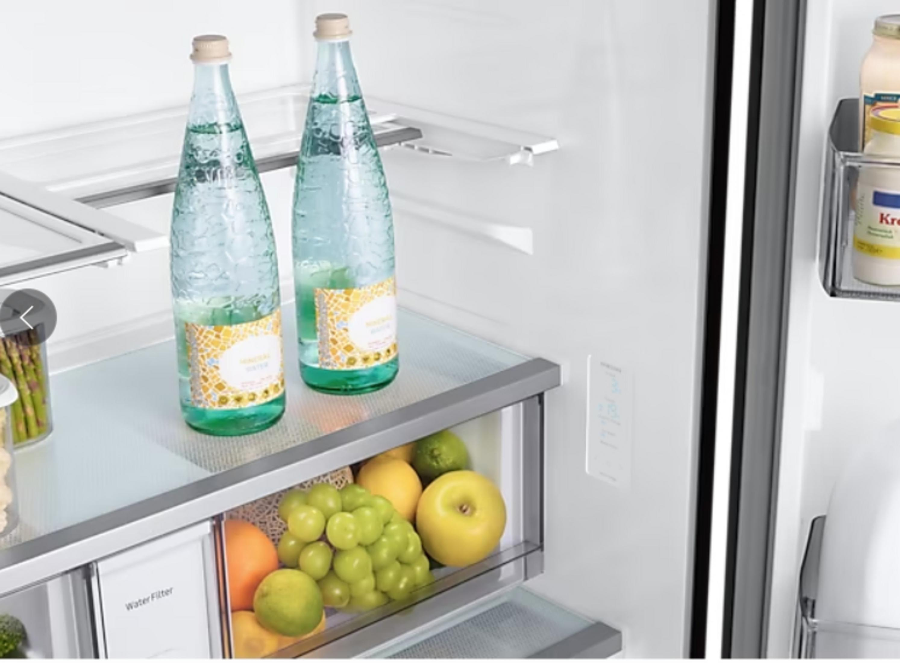 W lodówce: dwie butelki wody, winogrona, jabłka, pomarańcze, limonki i szparagi.