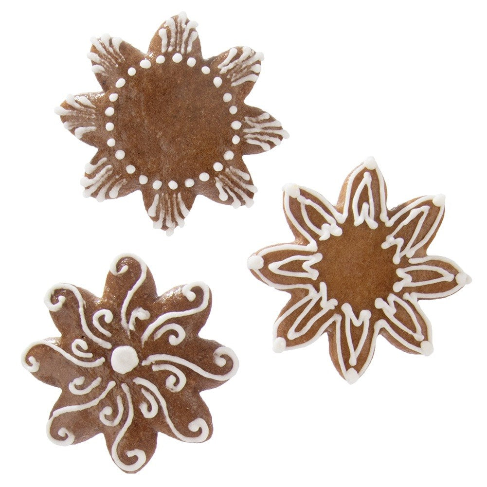 Tres galletas de jengibre en forma de estrella con glaseado blanco sobre fondo blanco.