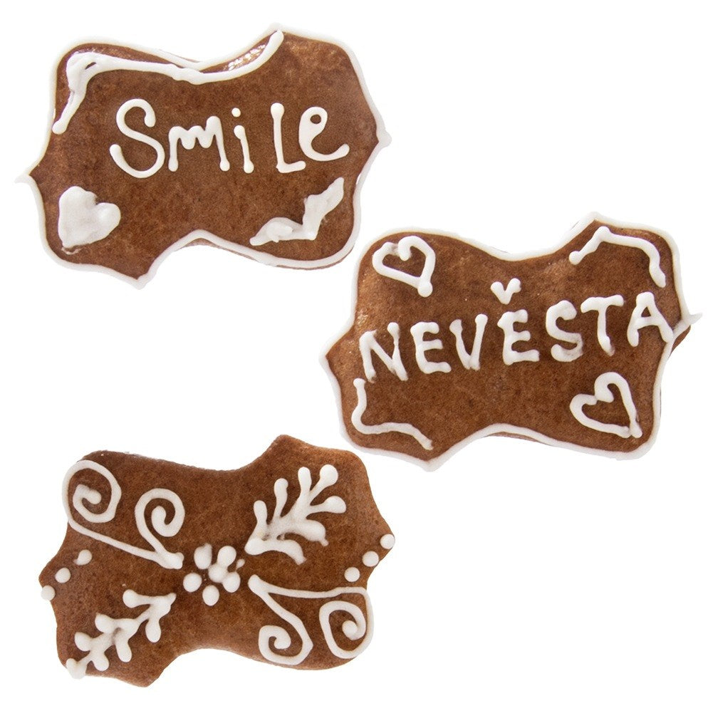 Tres galletas marrones con glaseado blanco. Una dice "Smile", otra dice "Nevesta".
