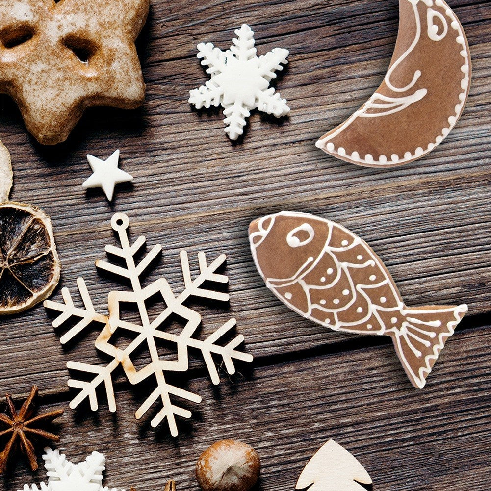 Galletas de jengibre con forma de pez y luna con decoración de copo de nieve sobre madera.
