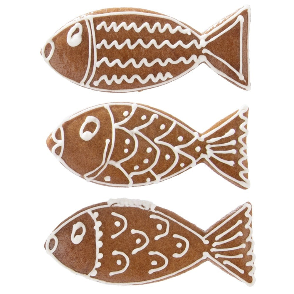 Tres galletas de jengibre en forma de pez con glaseado blanco.