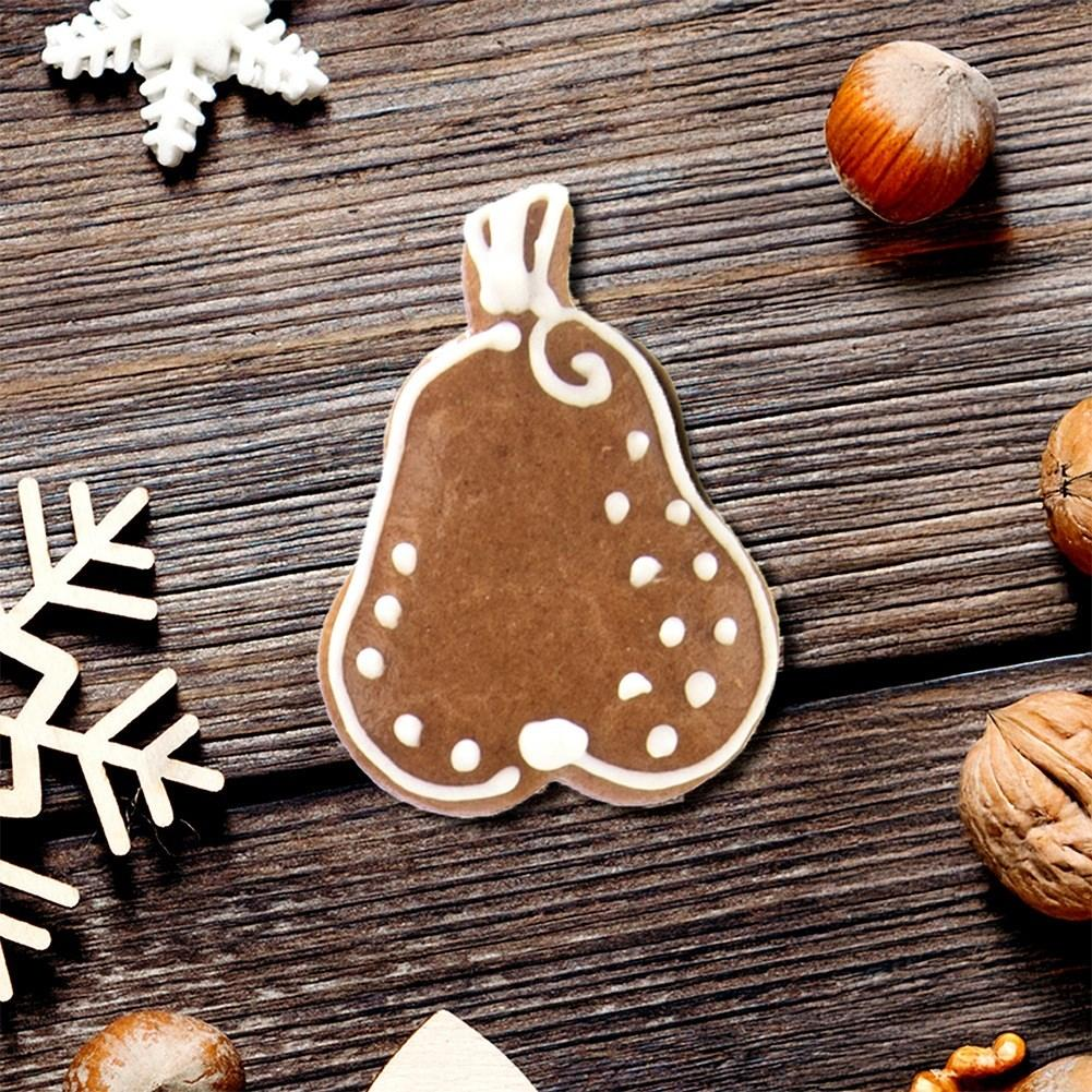 Galleta de jengibre en forma de pera con glaseado blanco sobre madera.