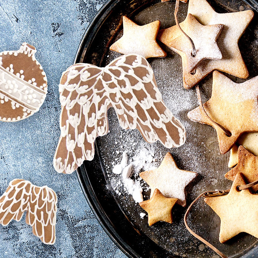 Galletas de Navidad: estrellas, alas y adorno en bandeja, espolvoreadas con azúcar.