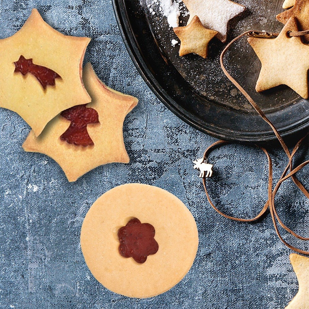 Galletas de estrella y redondas con relleno de mermelada en superficie azul.