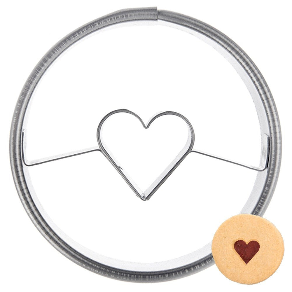 Un cortador redondo con forma de corazón y una galleta con relieve de corazón.